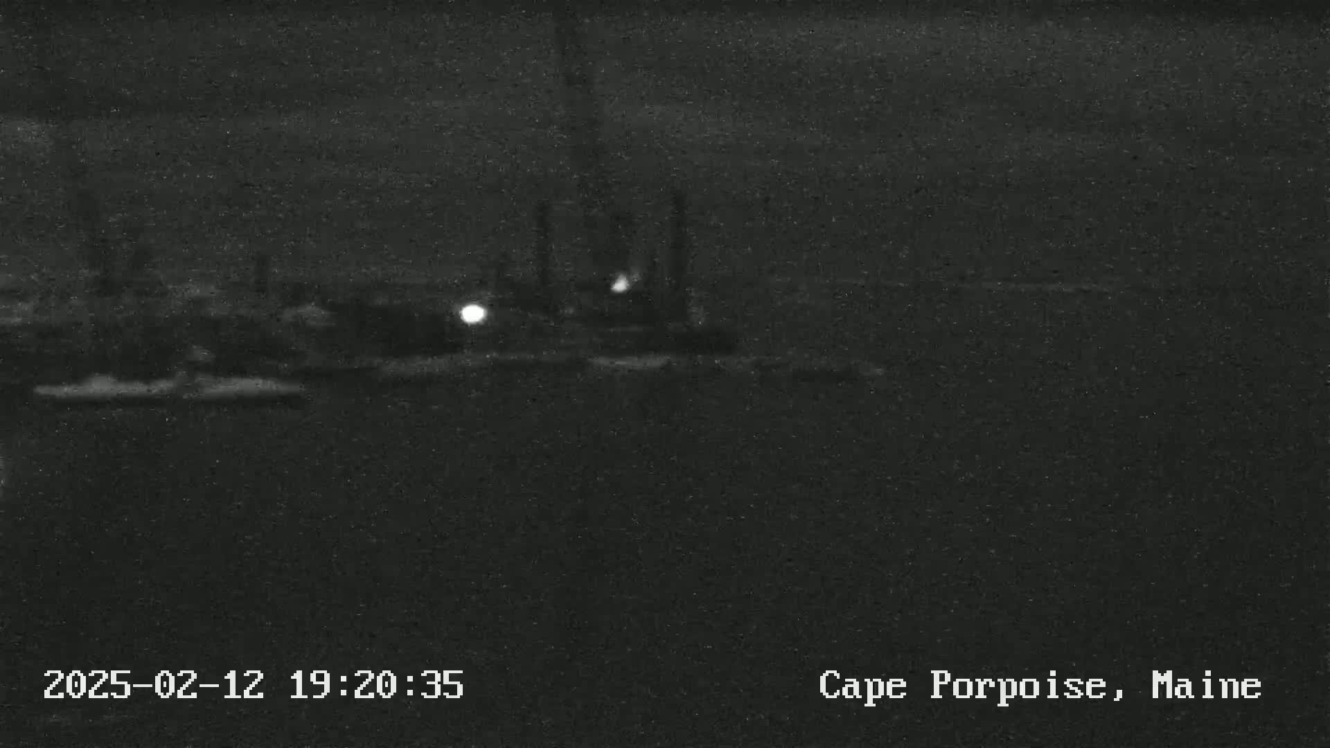 A nighttime, low-light view of a dark, possibly industrial, waterfront area.