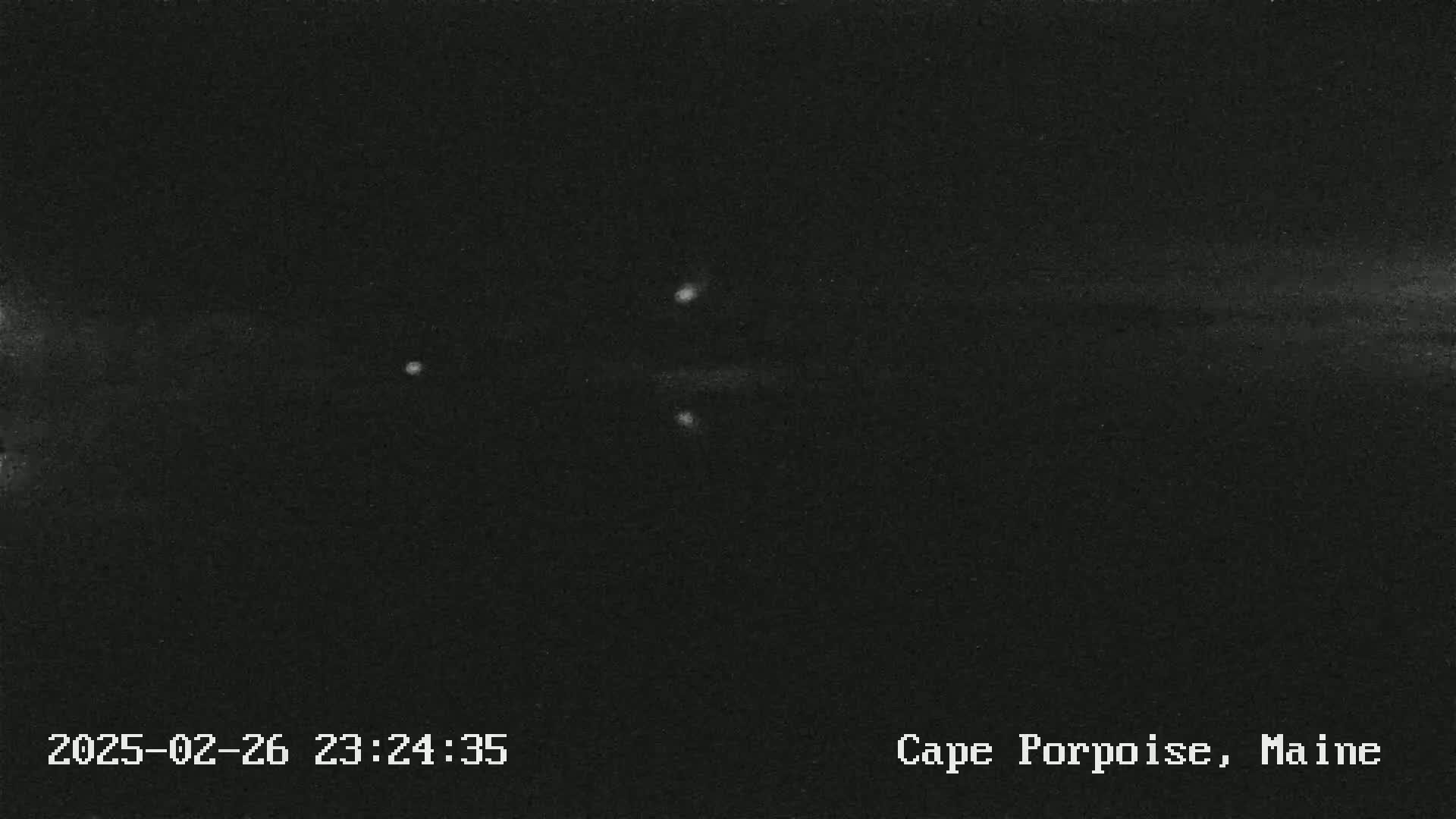 A nighttime long-exposure image shows a dark sky with several faint lights, possibly stars or distant lights.