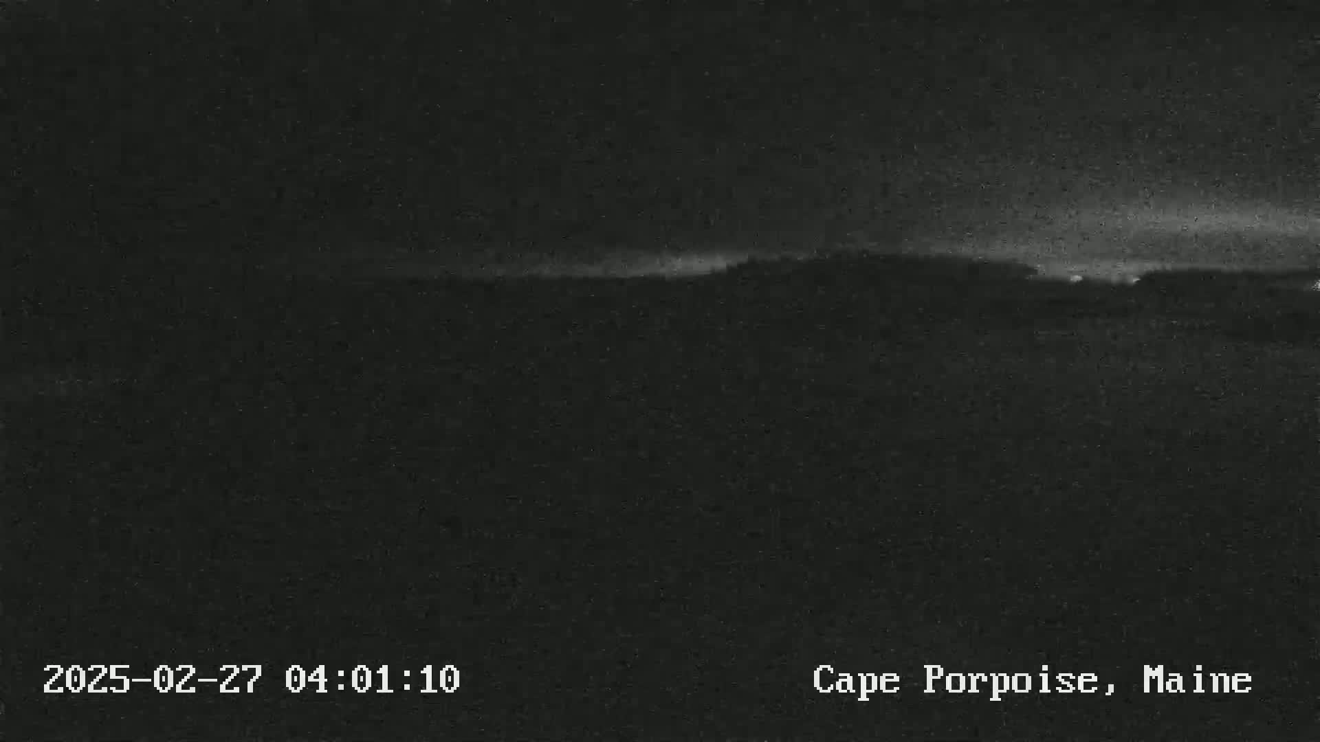 A dark, nighttime landscape is visible, with a slightly brighter horizon line suggesting a faint light source.