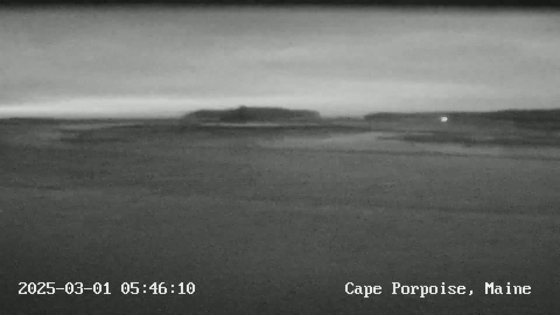 A dark, overcast landscape shows a flat expanse of land leading to a slightly elevated area in the distance.