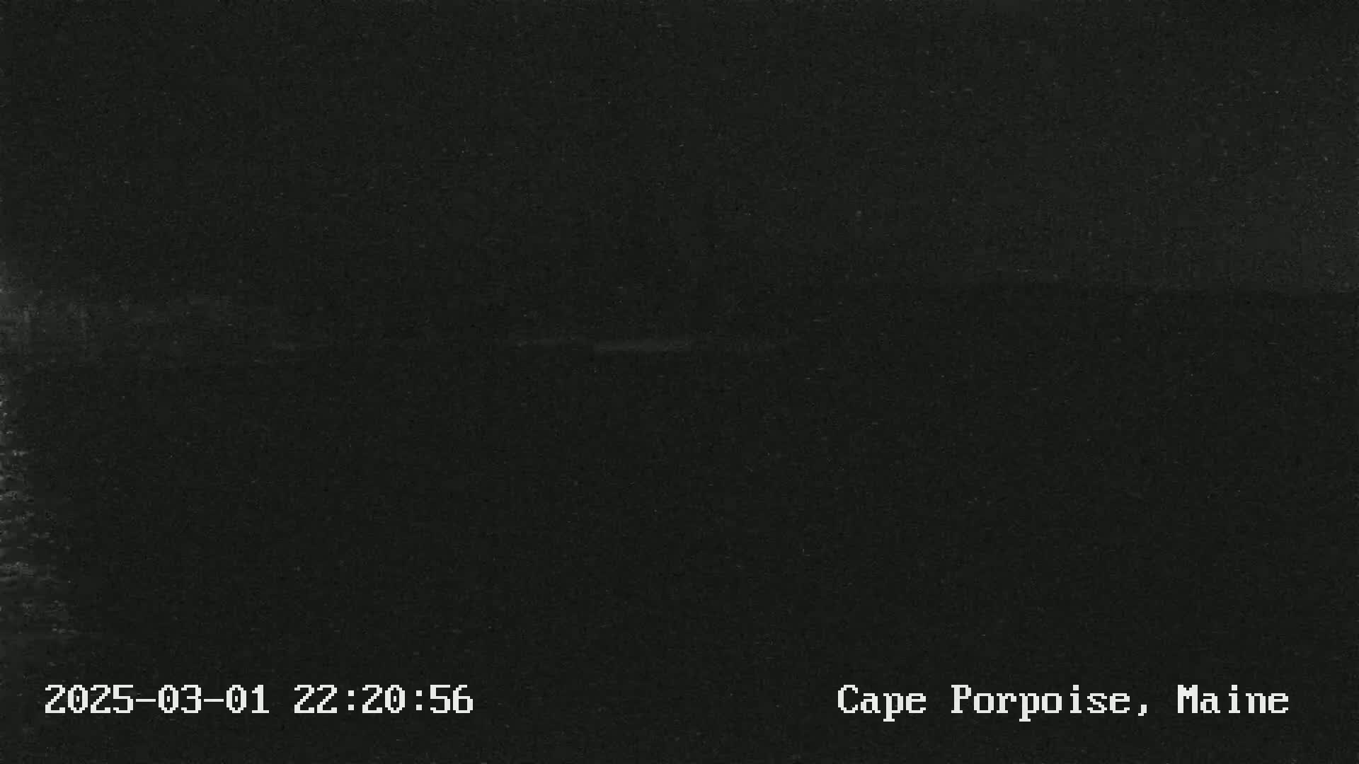 A nearly entirely black image shows a dark, possibly nighttime, outdoor scene with a barely visible horizon line.
