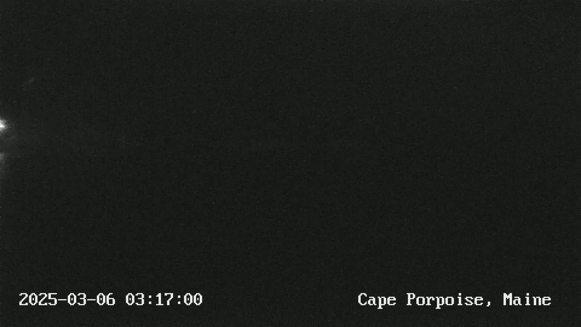 A dark, nighttime image shows a mostly black sky with a faint, bright area on the left.