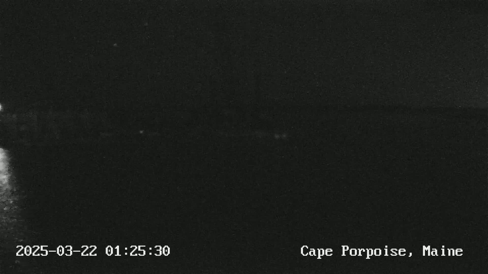 A nighttime, dark image shows a mostly black scene with a faint, lighter horizontal line possibly representing a horizon under a clear sky.