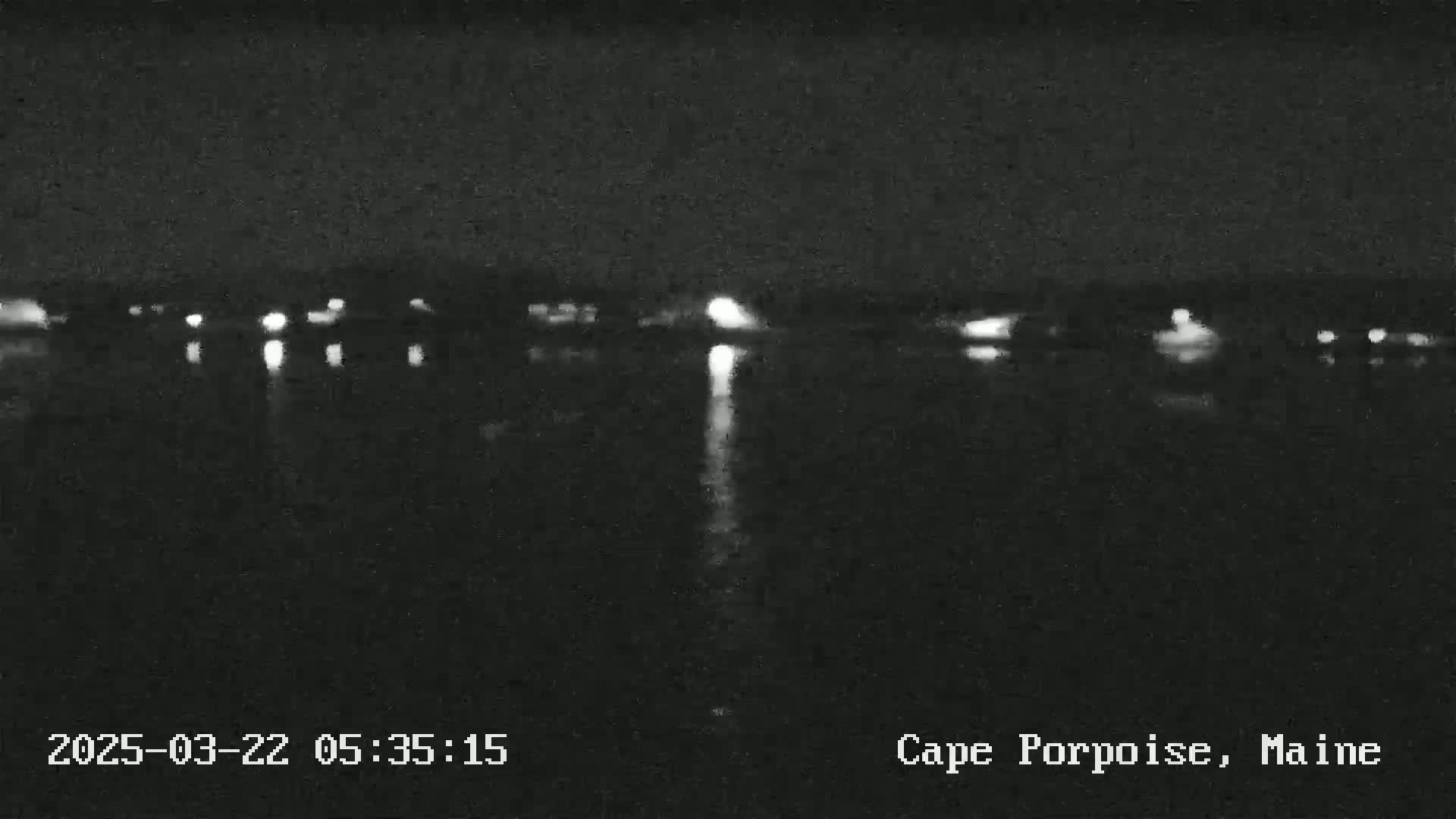 A nighttime view of a body of water reflecting distant lights under a dark sky.