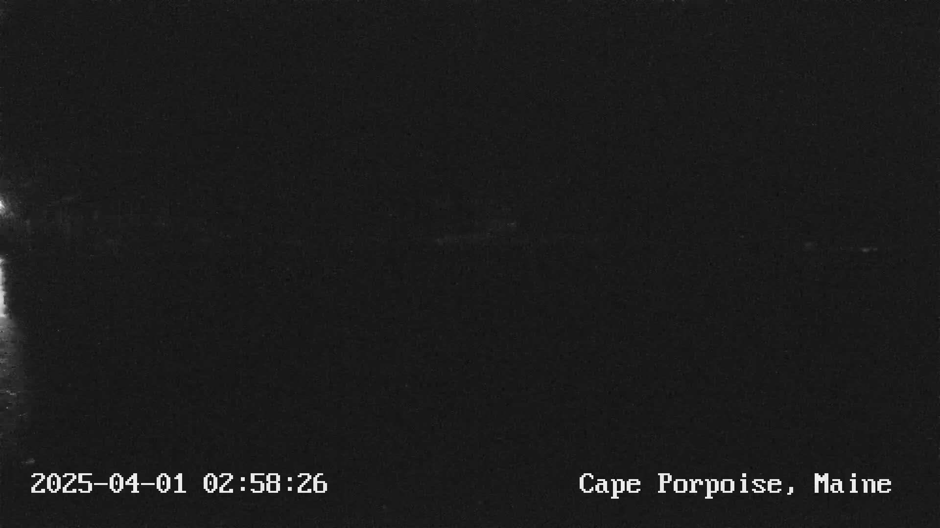 A very dark, nighttime image shows a mostly black scene with a faint, brighter horizontal line near the middle.