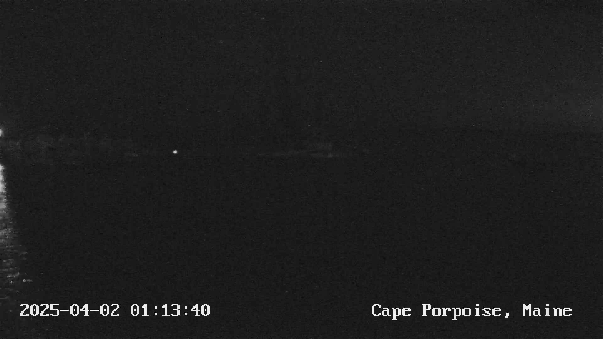 A dark, nighttime image shows a faint, blurry horizon line under a clear, dark sky.