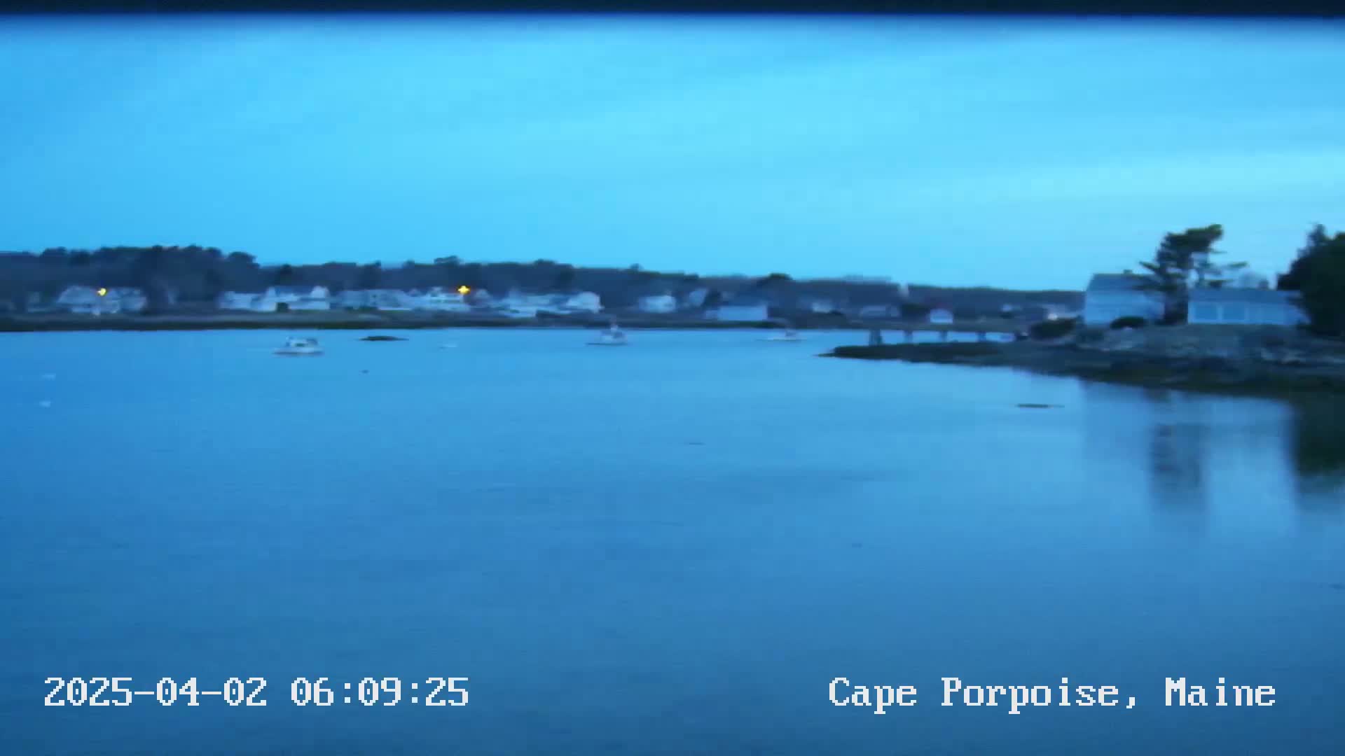 A calm, blue-tinged body of water reflects the twilight sky, with a small coastal town visible in the background.