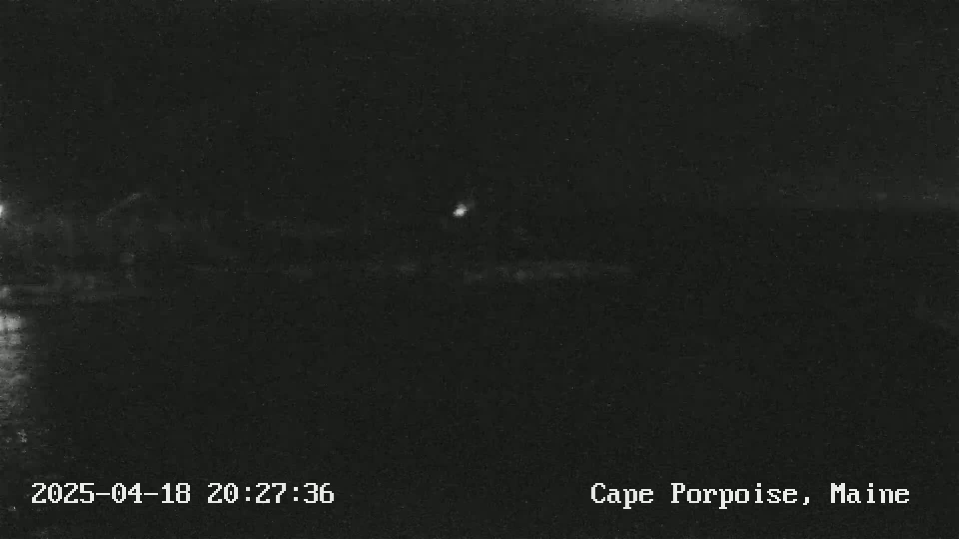 A dark, nighttime scene shows a faint light in the distance.