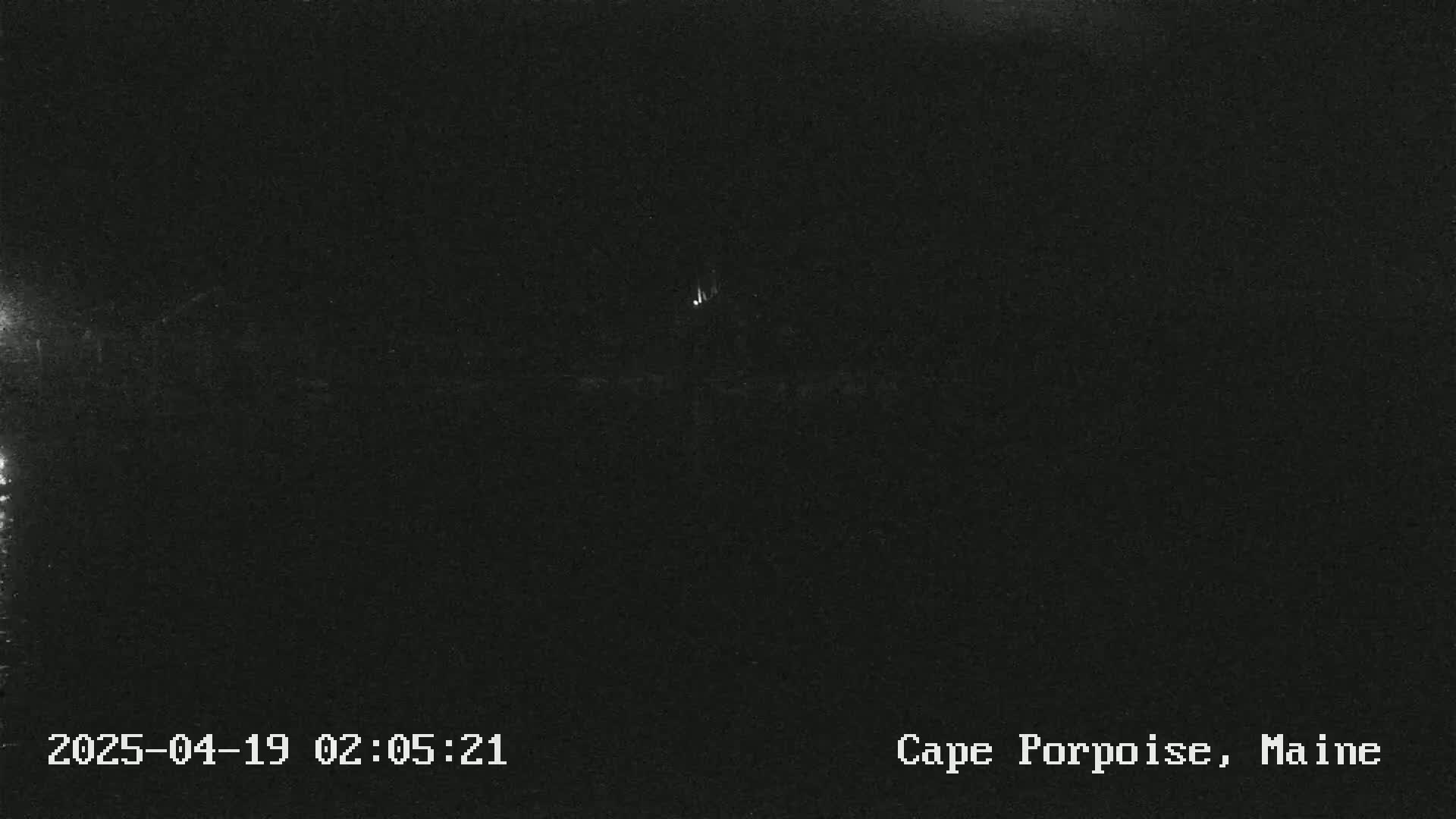 A dark, nighttime scene shows a faint light in the distance.