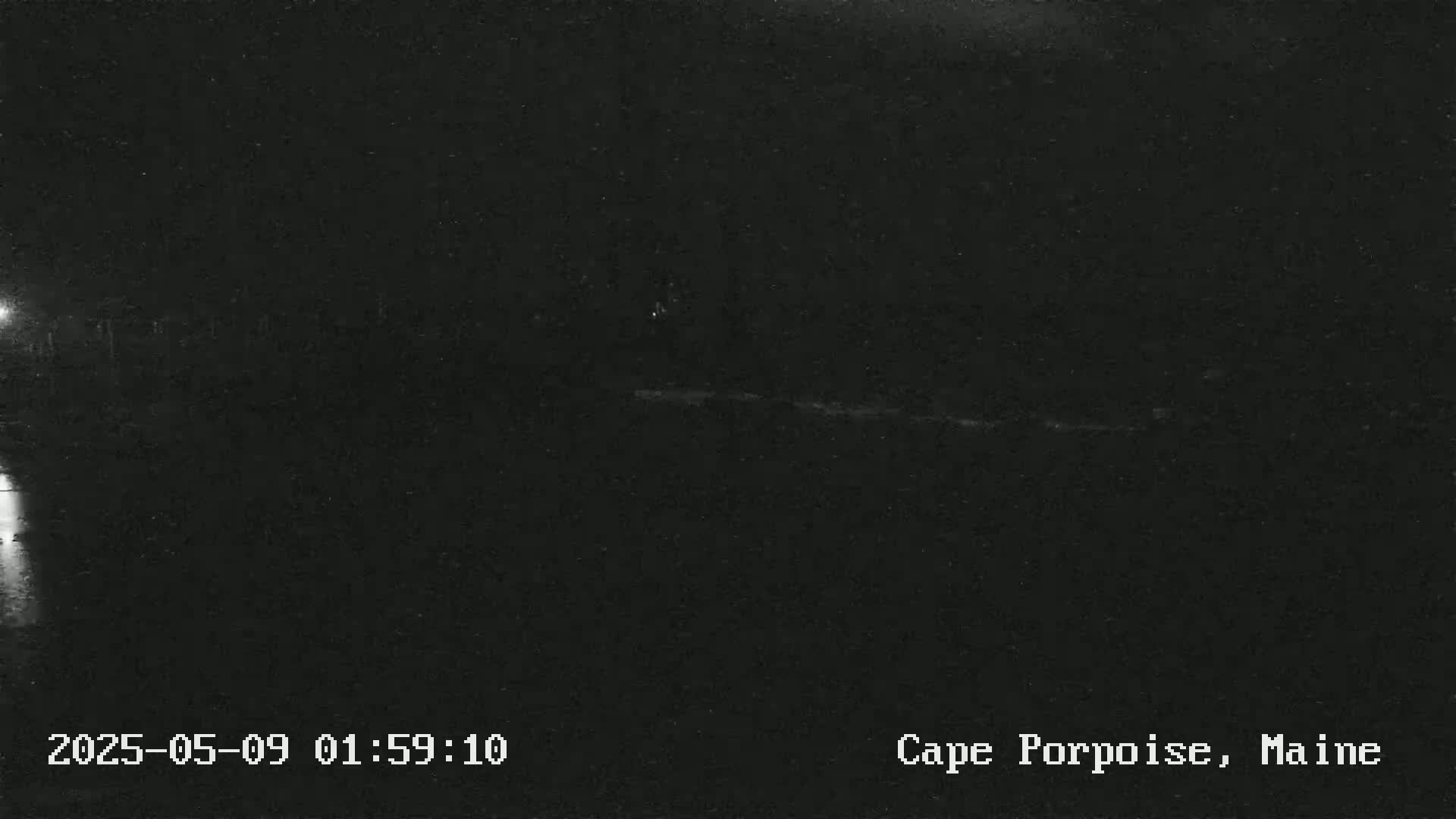 A dark, nighttime outdoor scene shows a mostly black landscape with a faint, light horizontal line in the middle.