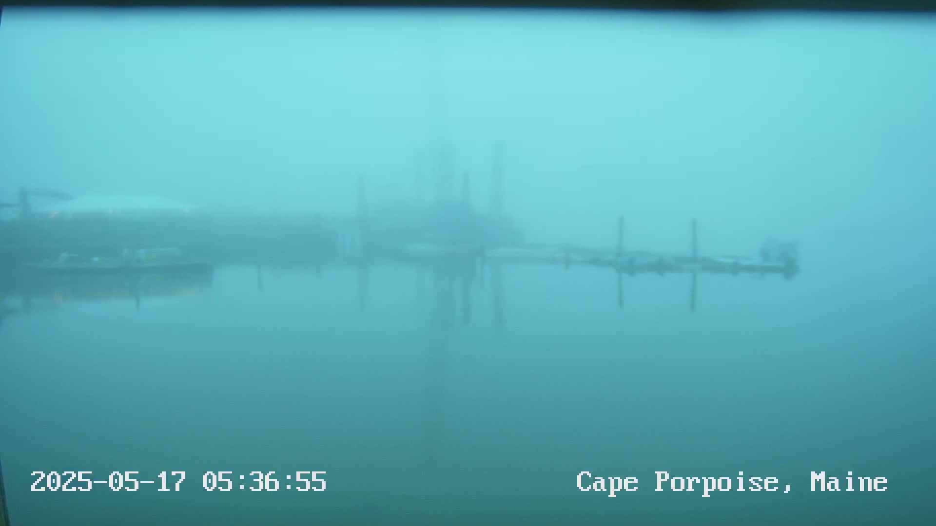 A hazy, foggy view of a pier and calm water.