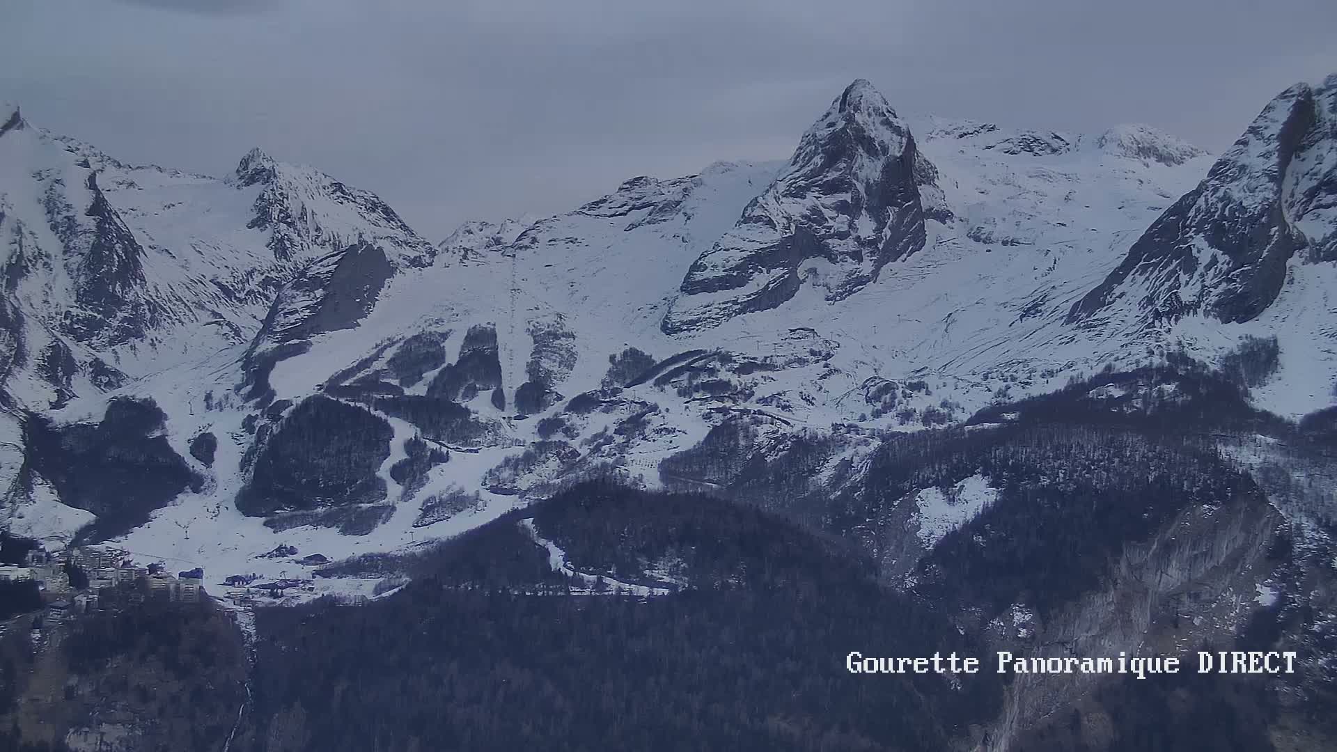 Snow-covered mountains with a valley below under an overcast sky.