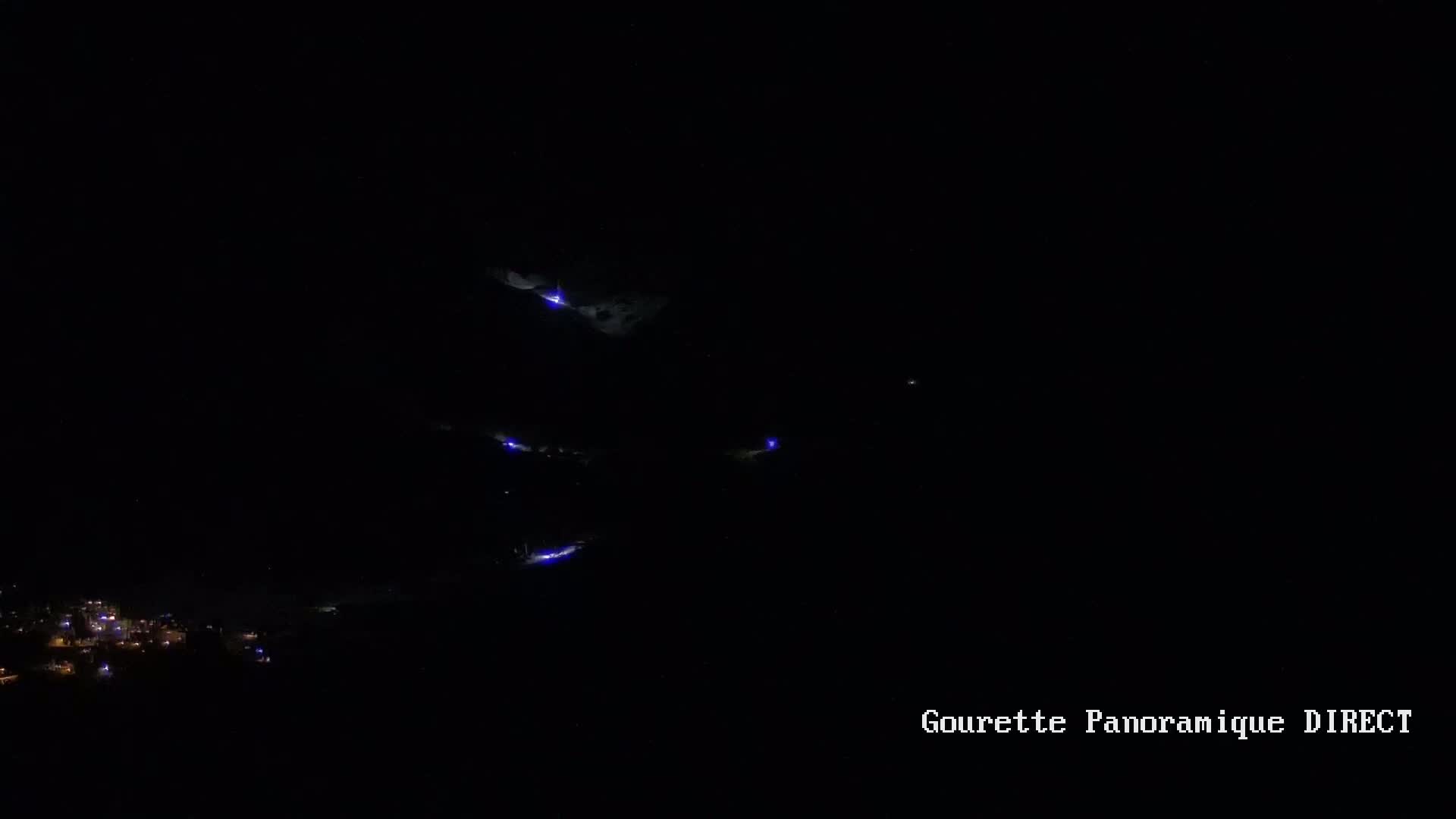 A nighttime long shot shows a mountain range with a few faint lights visible, possibly from a town in the distance.