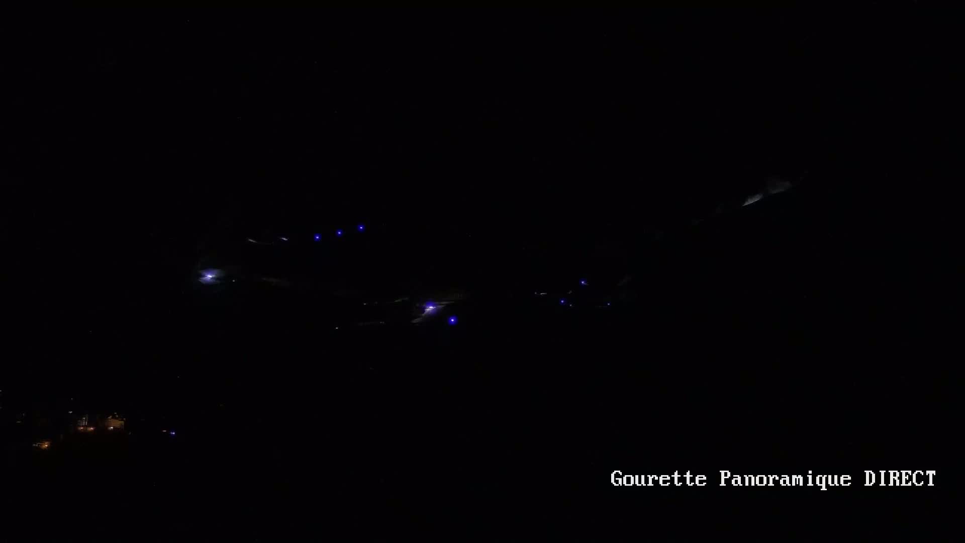At night, several small, bright lights are visible in the dark sky, possibly from aircraft or other distant light sources.