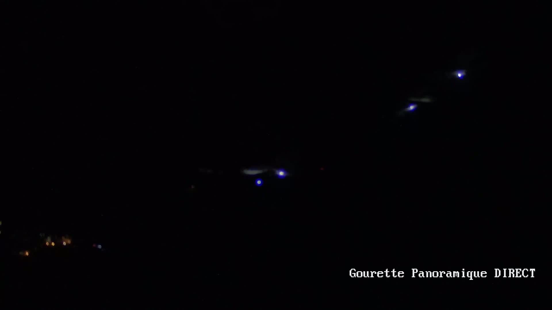 Several faint lights are visible in the night sky, appearing as blurry streaks and points of light.