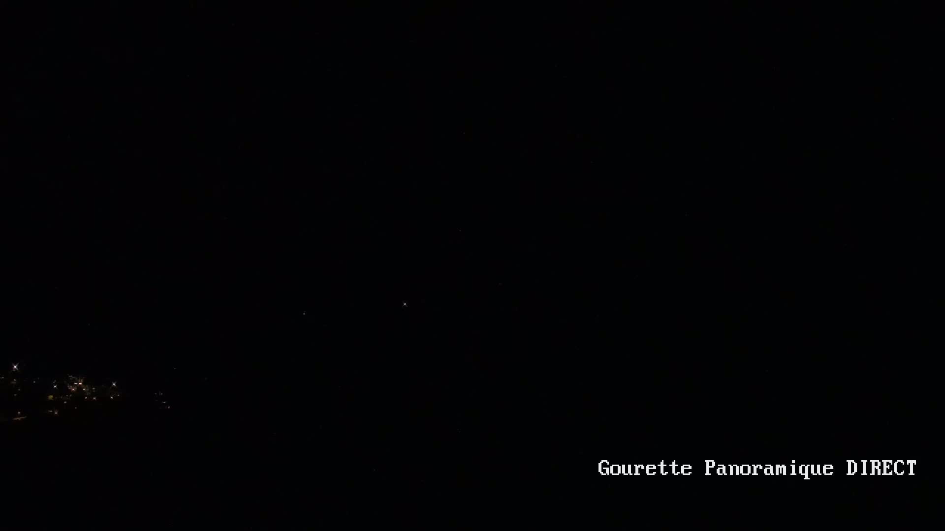 A dark nighttime scene shows a few faint lights in the distance.