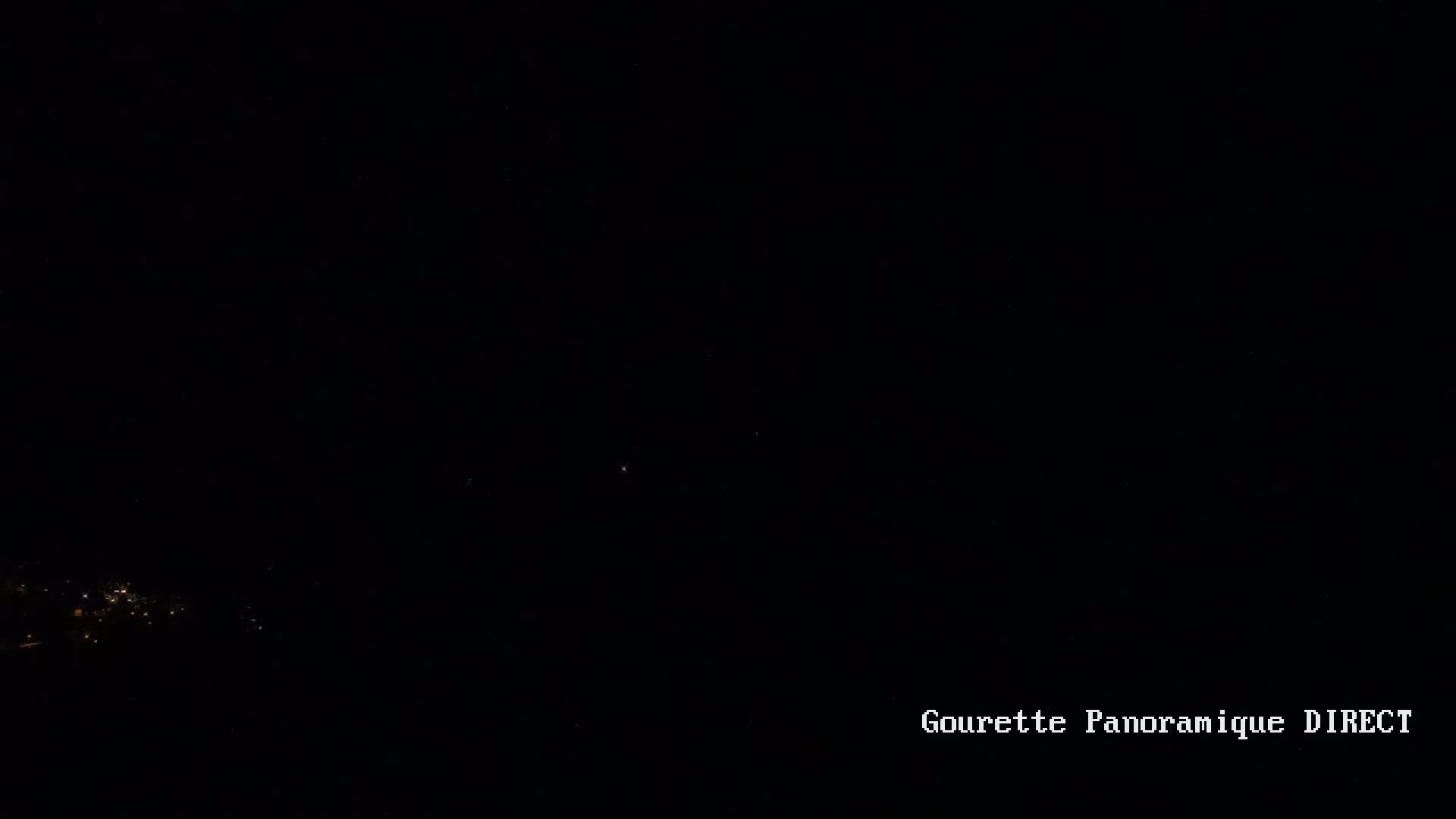 A nighttime view of a small cluster of lights in the distance against a dark sky.