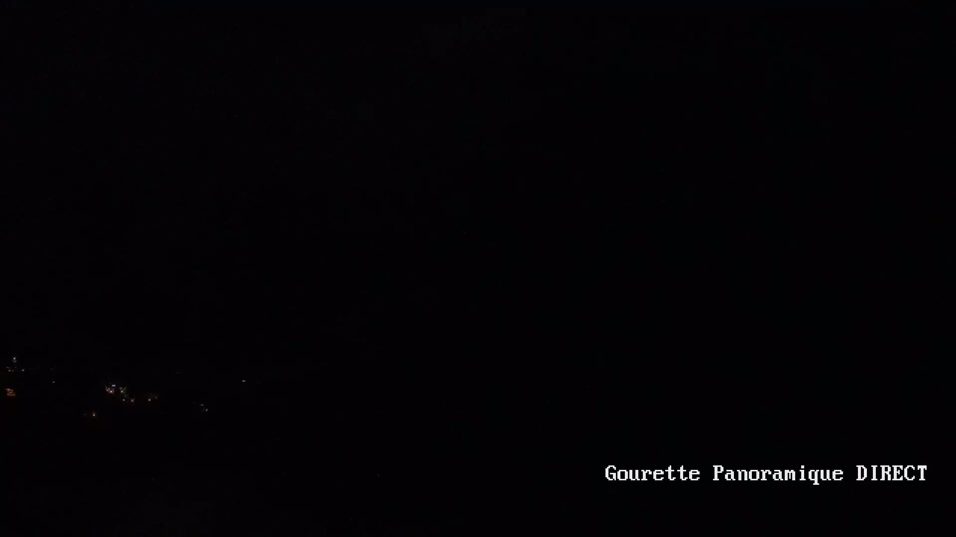 A dark nighttime scene shows a few faint lights in the distance.