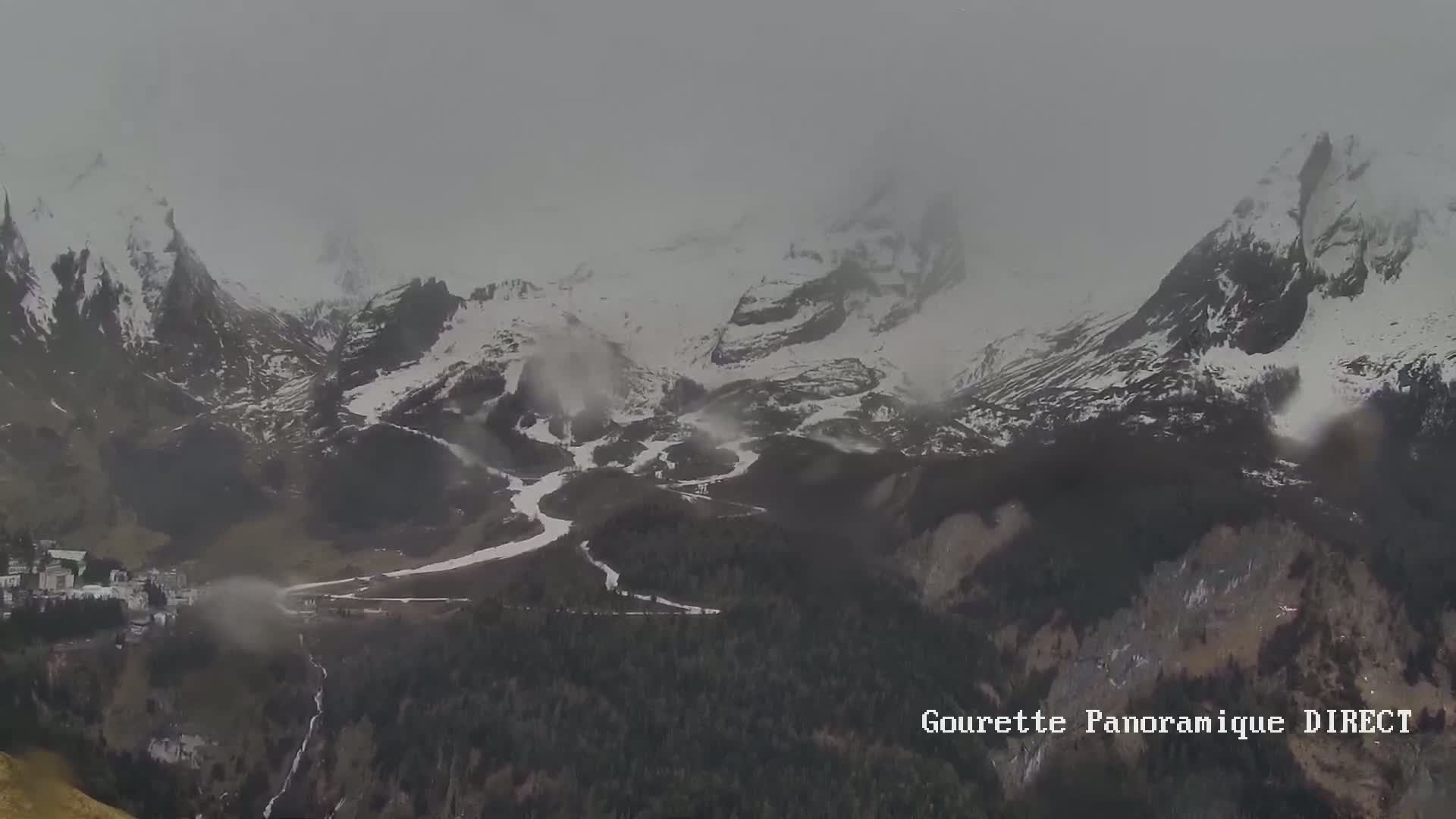 A distant view of snow-capped mountains and a valley below, partially obscured by fog or mist.