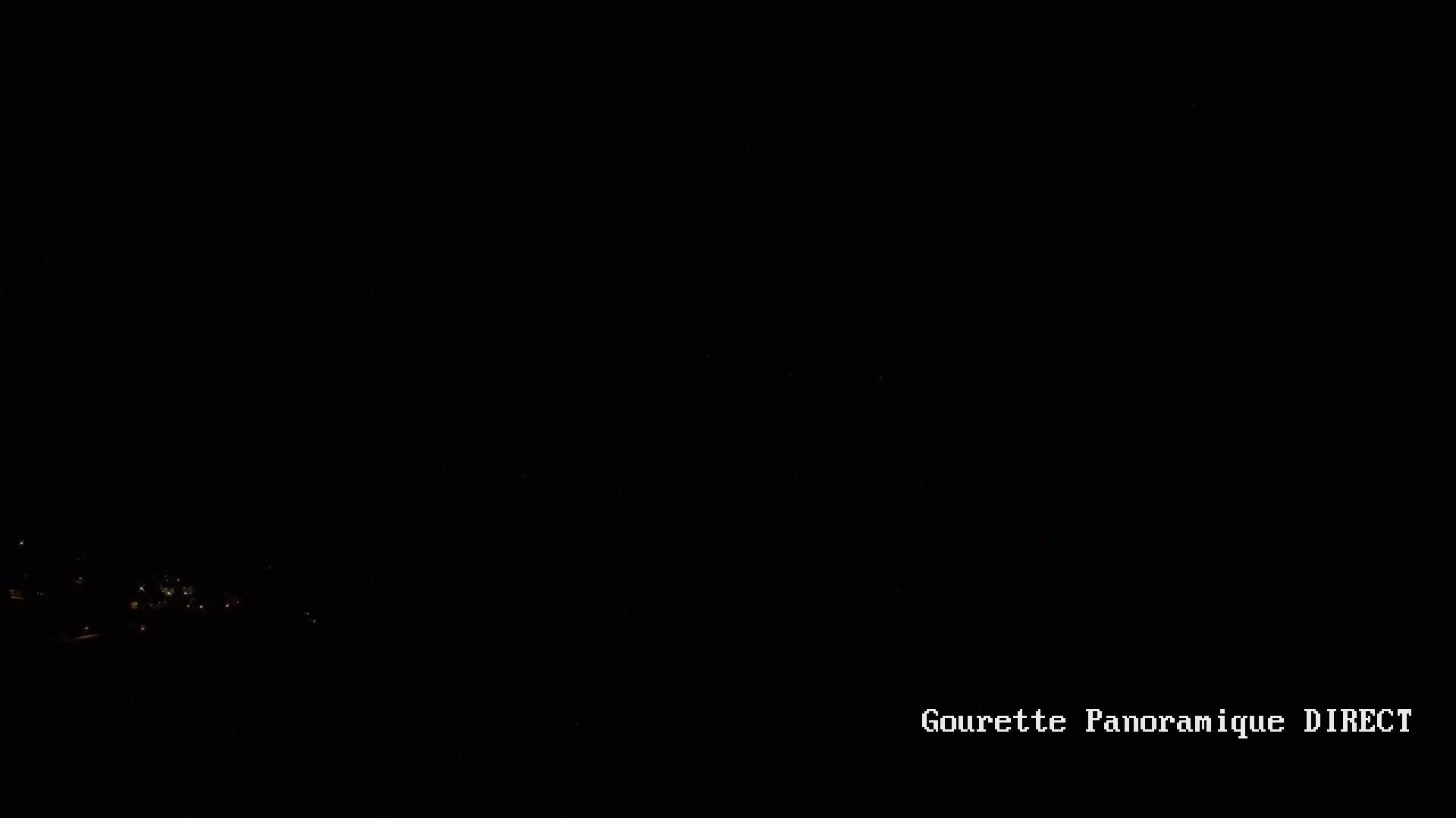 A nighttime, long-range view shows a few faint lights in the distance at the bottom of the frame.