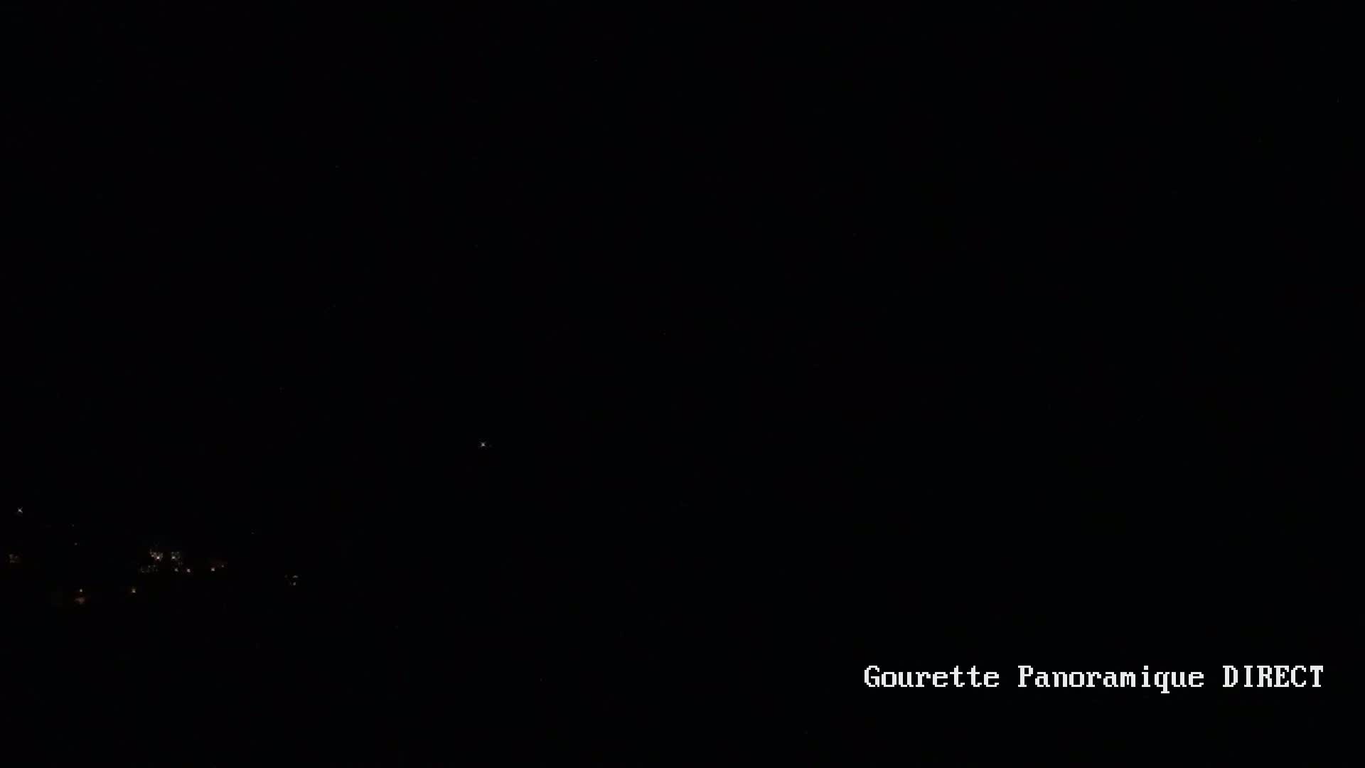 A dark nighttime scene shows a few faint lights in the distance.