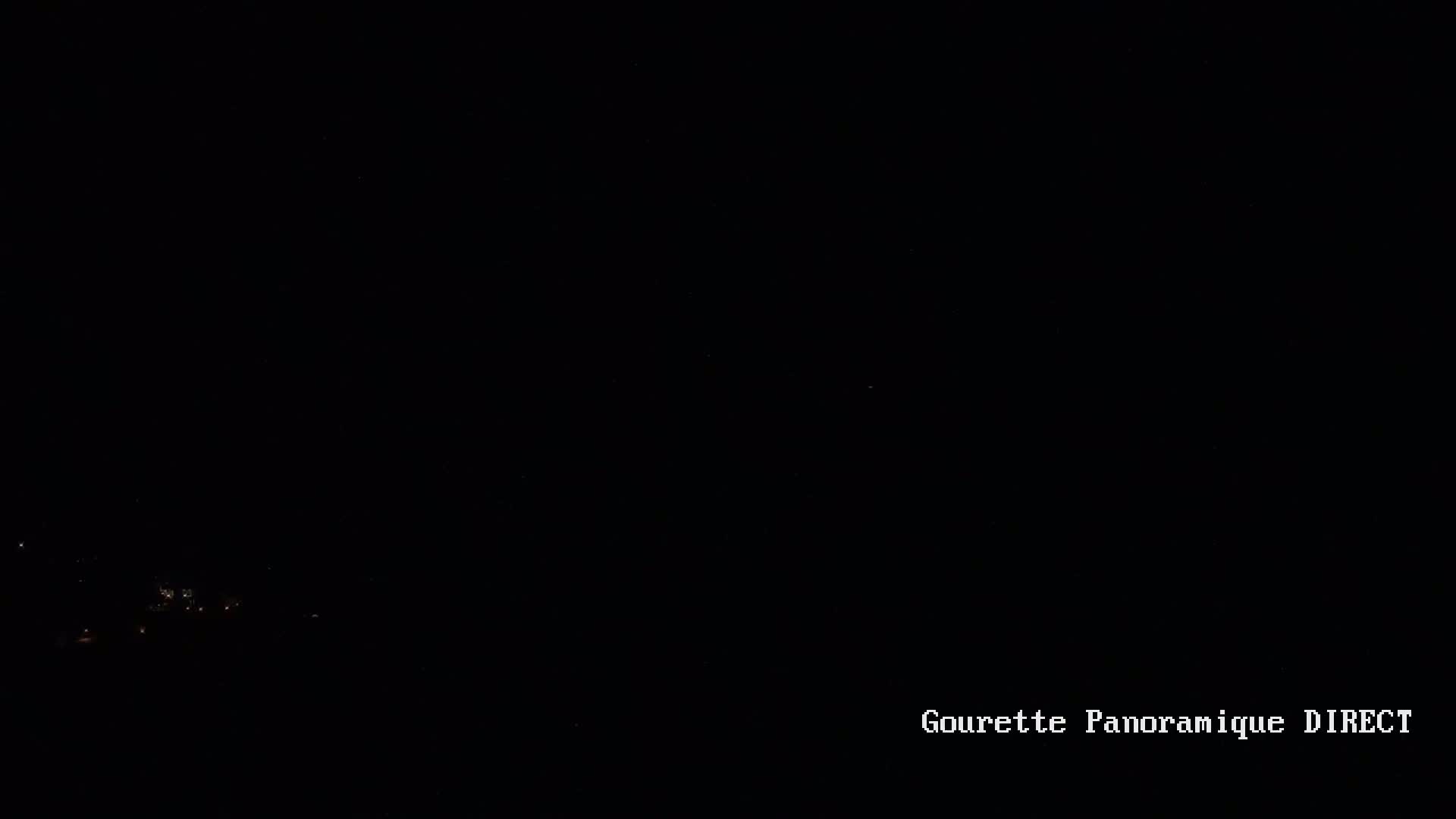 A dark nighttime scene shows a few faint lights in the distance.