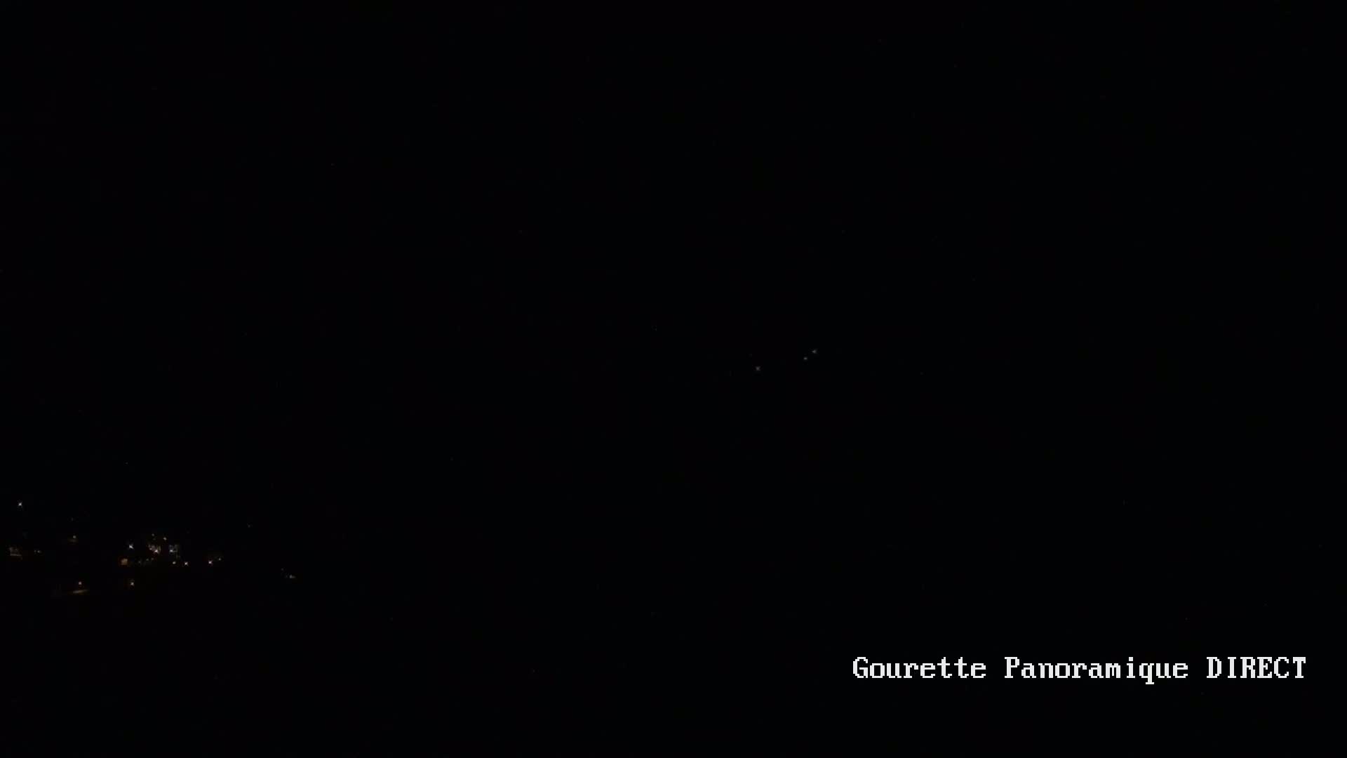 A nighttime long shot shows a few faint lights in the distance against a dark sky.