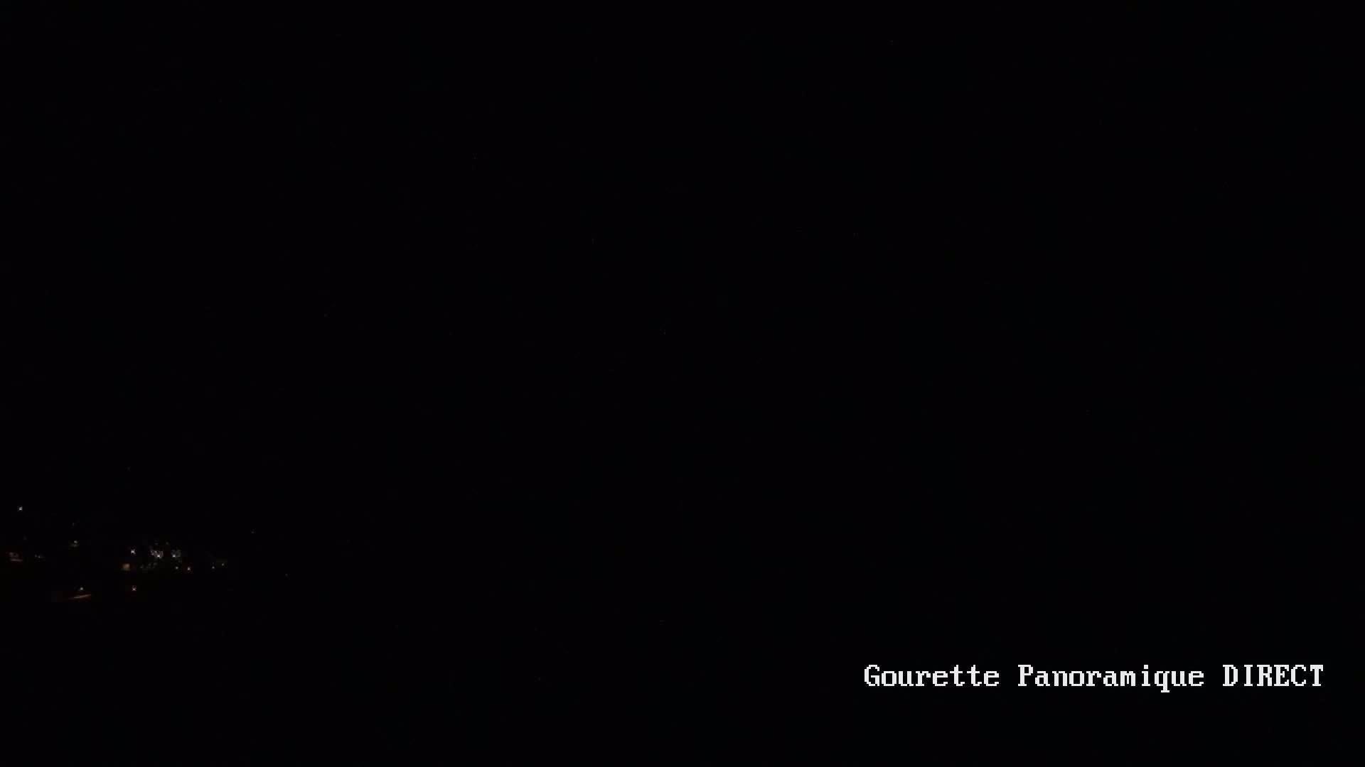 A dark, nighttime scene shows a few faint lights in the distance.