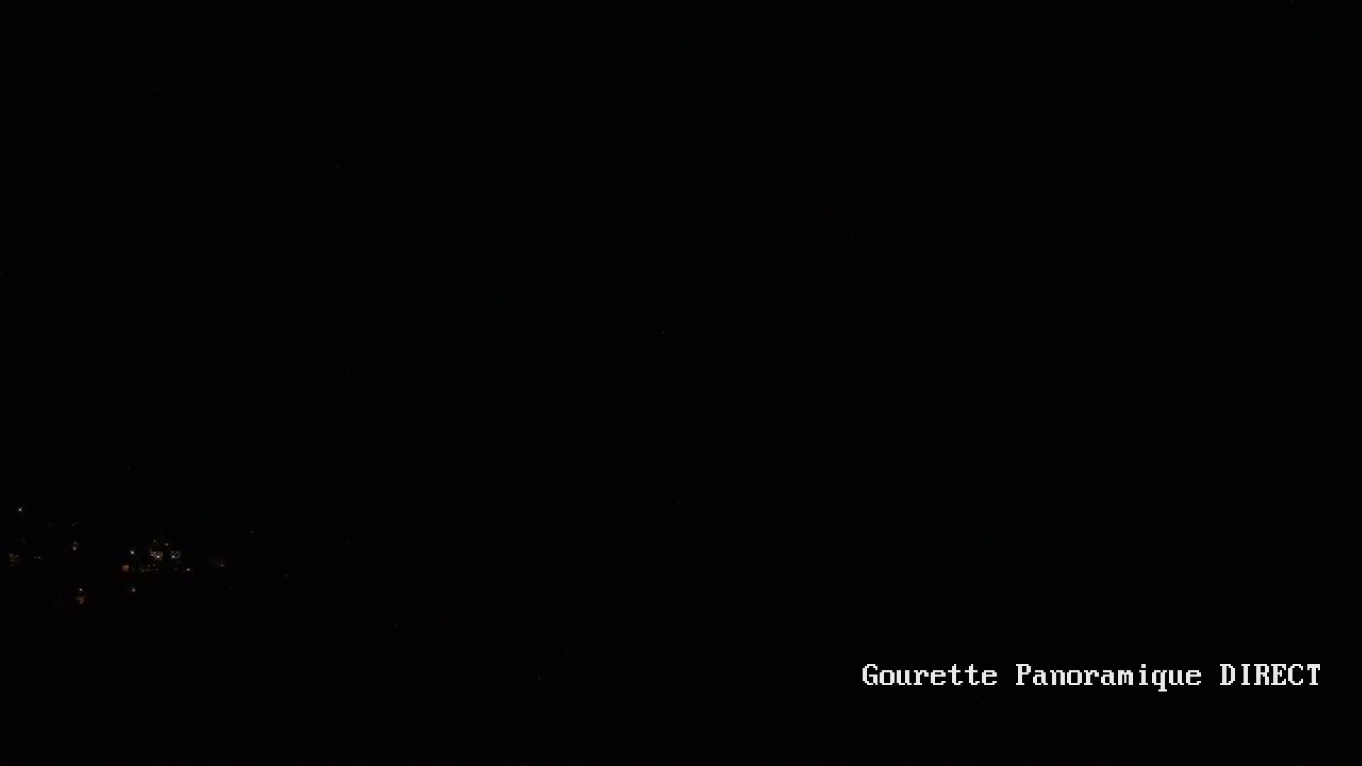 A nighttime, long-range view of dimly lit buildings or a small town under a dark sky.