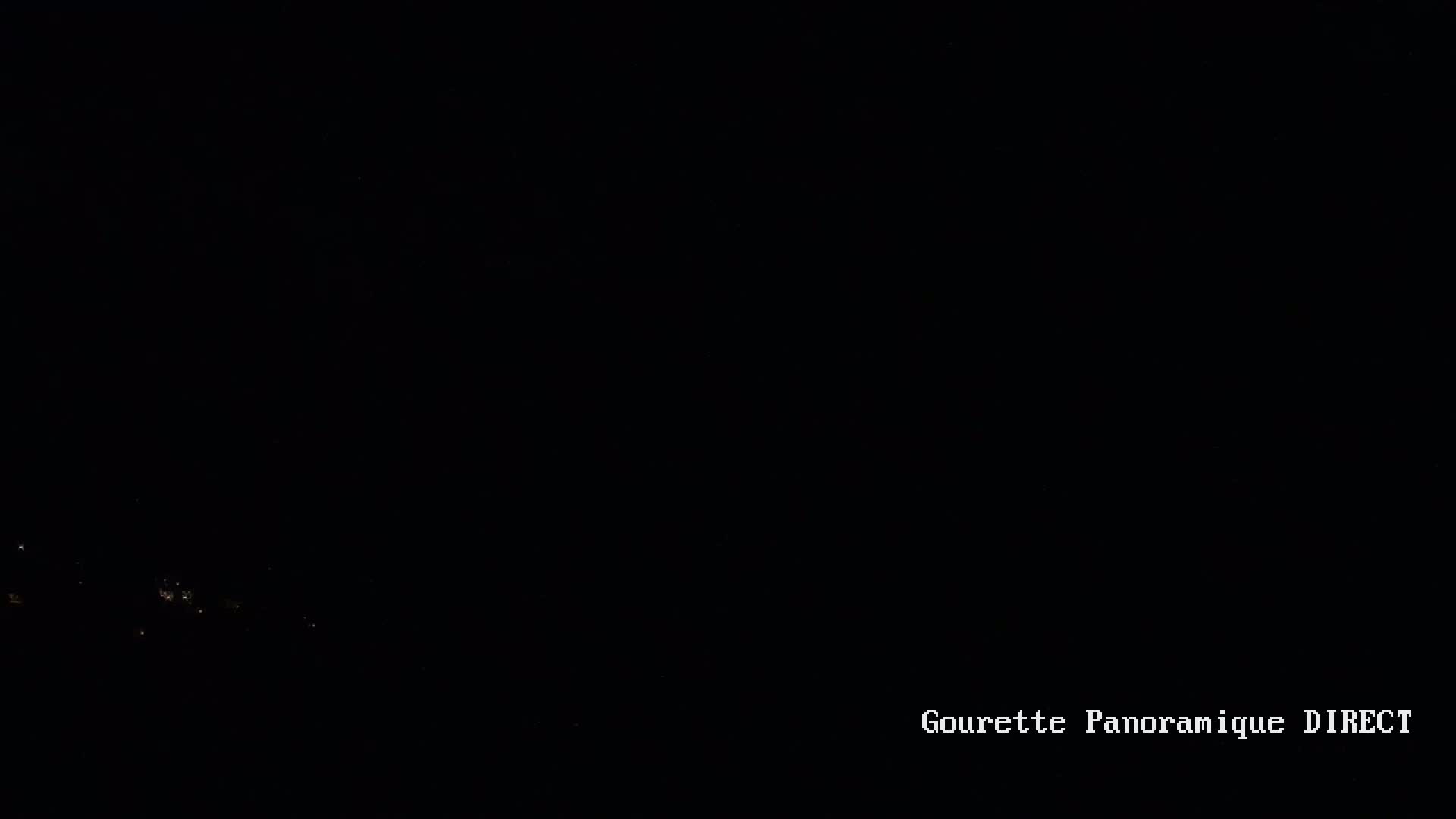 A dark, nighttime scene shows a few faint lights in the distance.