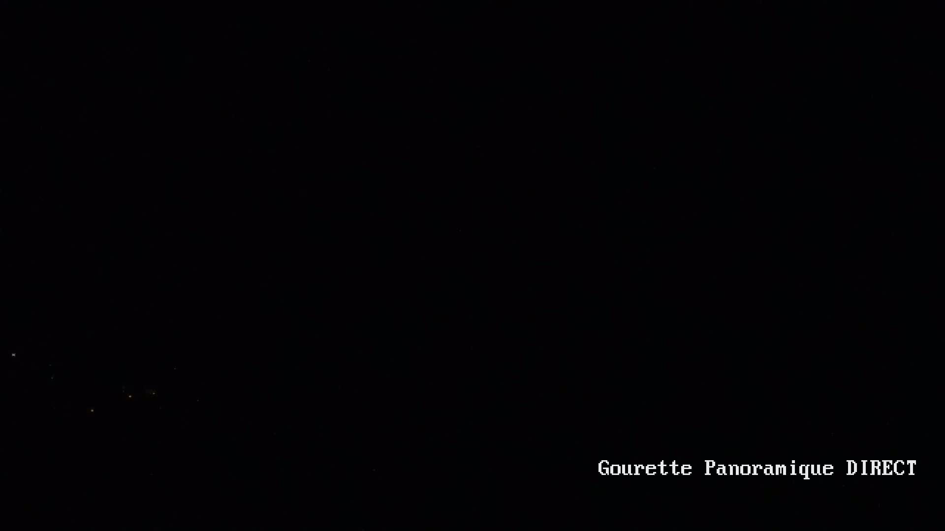 A nearly completely dark, nighttime scene shows a few faint lights in the distance.