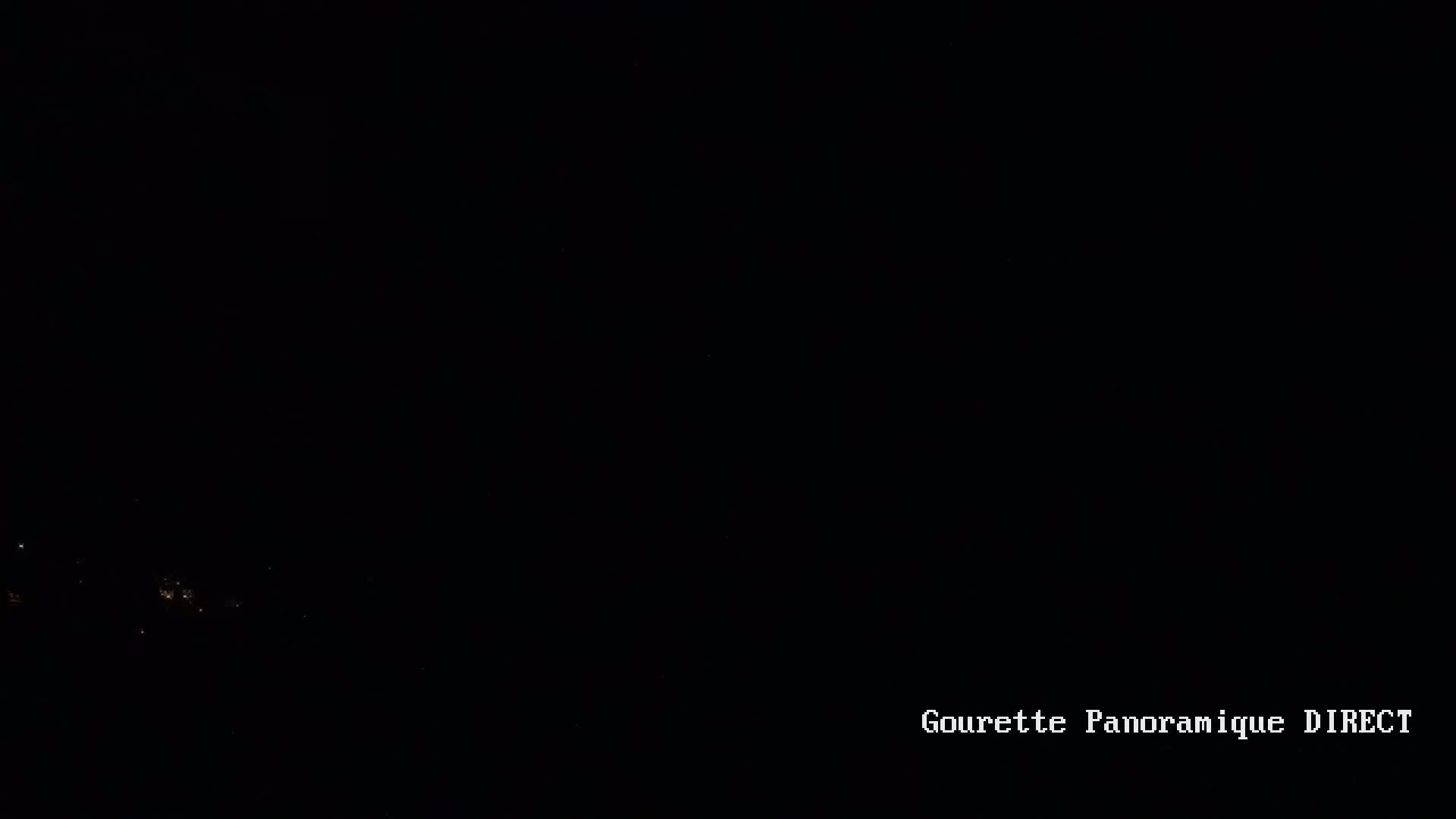 A dark, nighttime scene shows a few faint lights in the distance.
