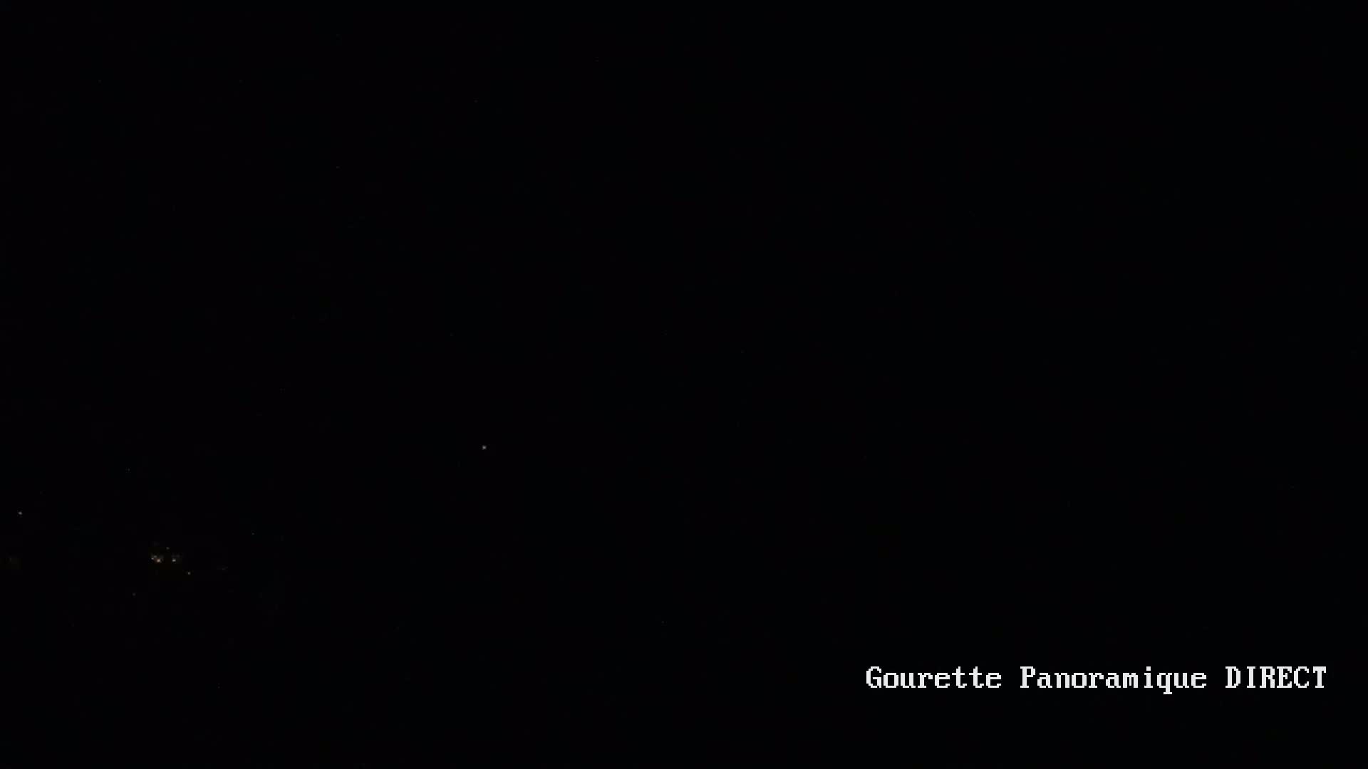A nighttime image shows a dark sky with a few faint lights visible in the distance.