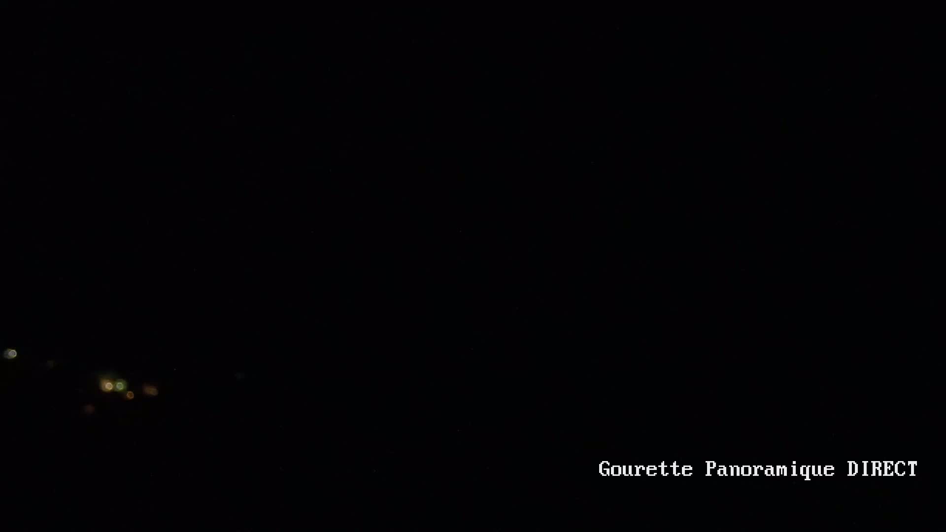 A dark nighttime scene shows a few blurry lights in the distance.