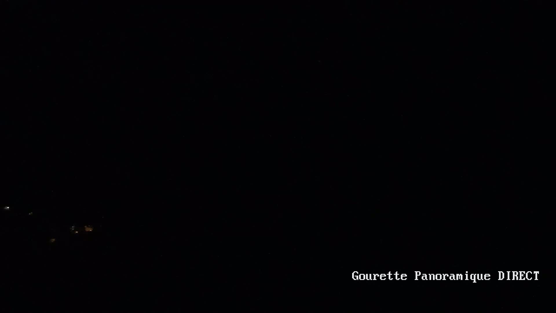 A dark nighttime scene shows a few faint lights in the distance.