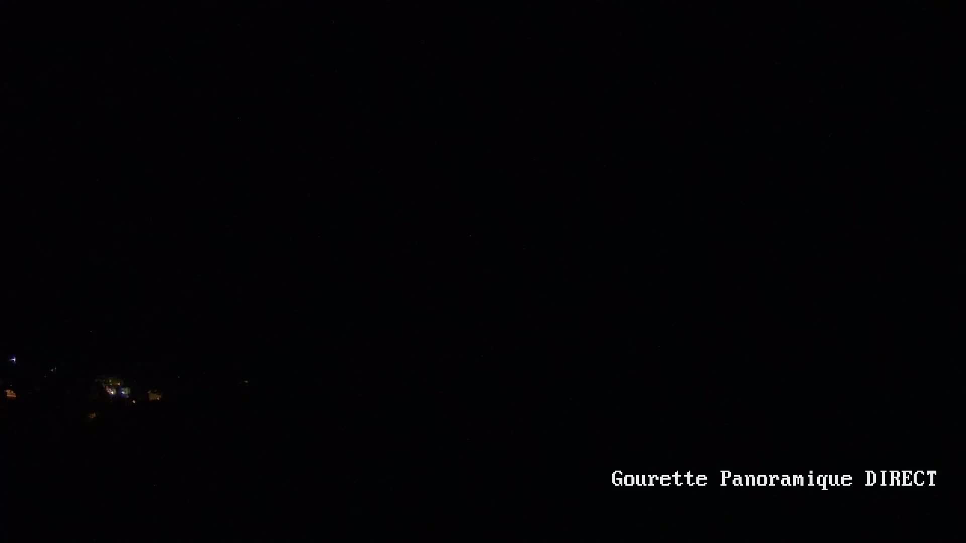 A nighttime, long-distance view shows a scattering of faint lights in the dark distance.