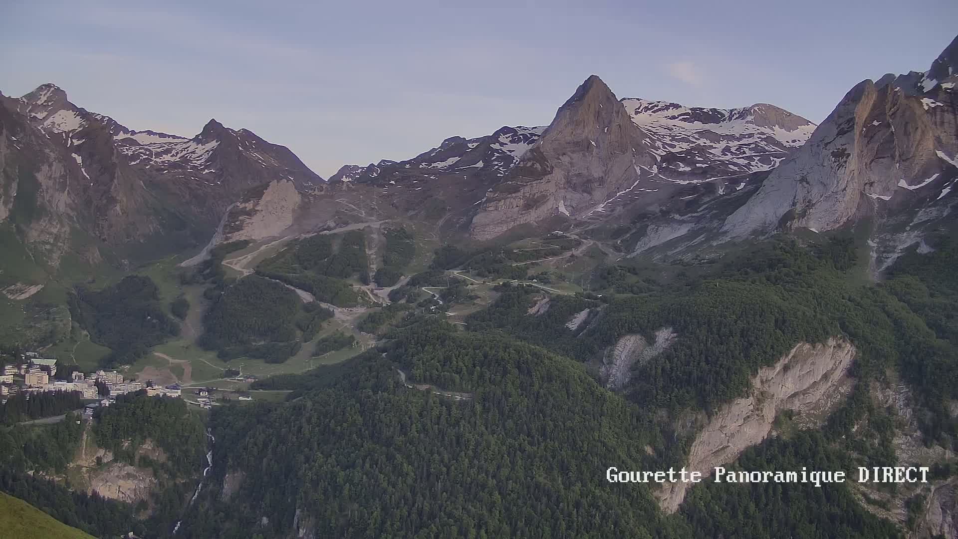 A mountain valley town nestled amongst snow-capped, rocky mountains under a clear, twilight sky.