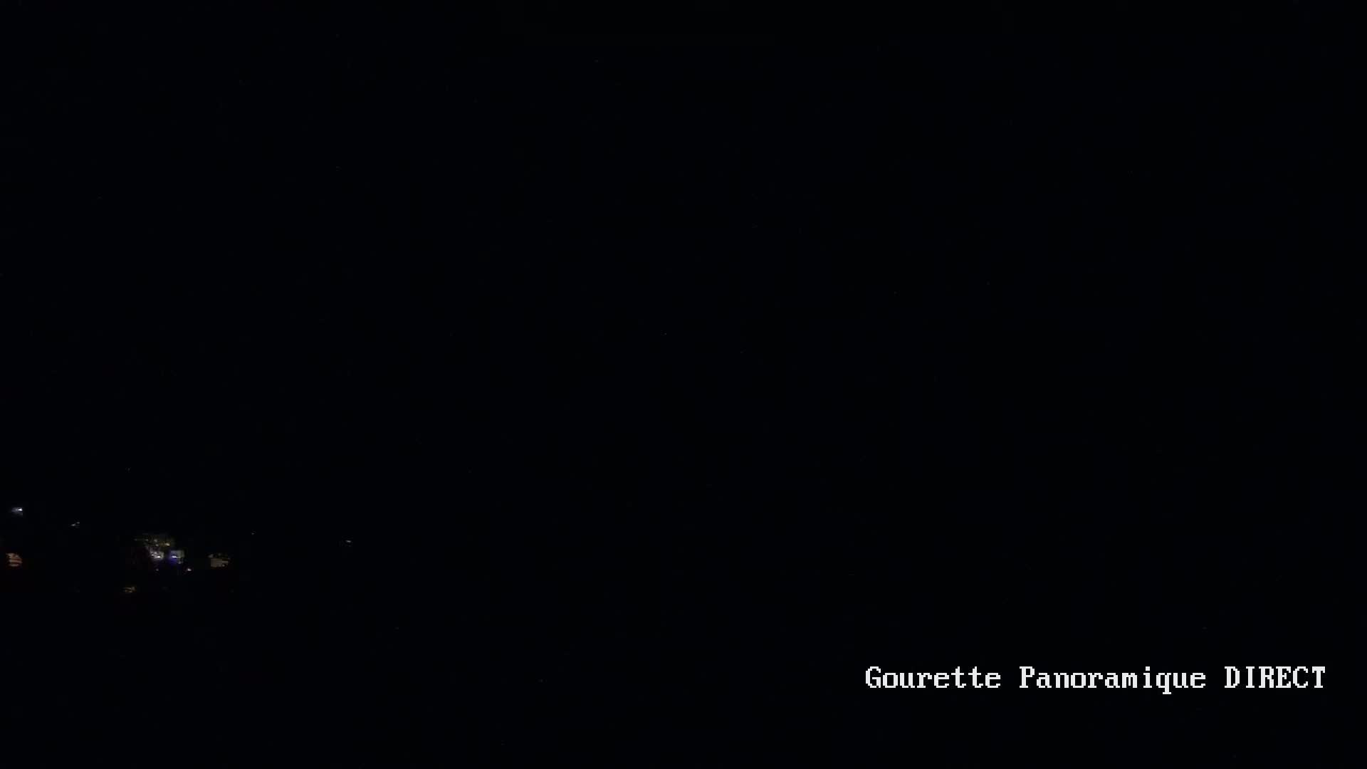 A nighttime view of faintly lit structures in the distance under a dark sky.