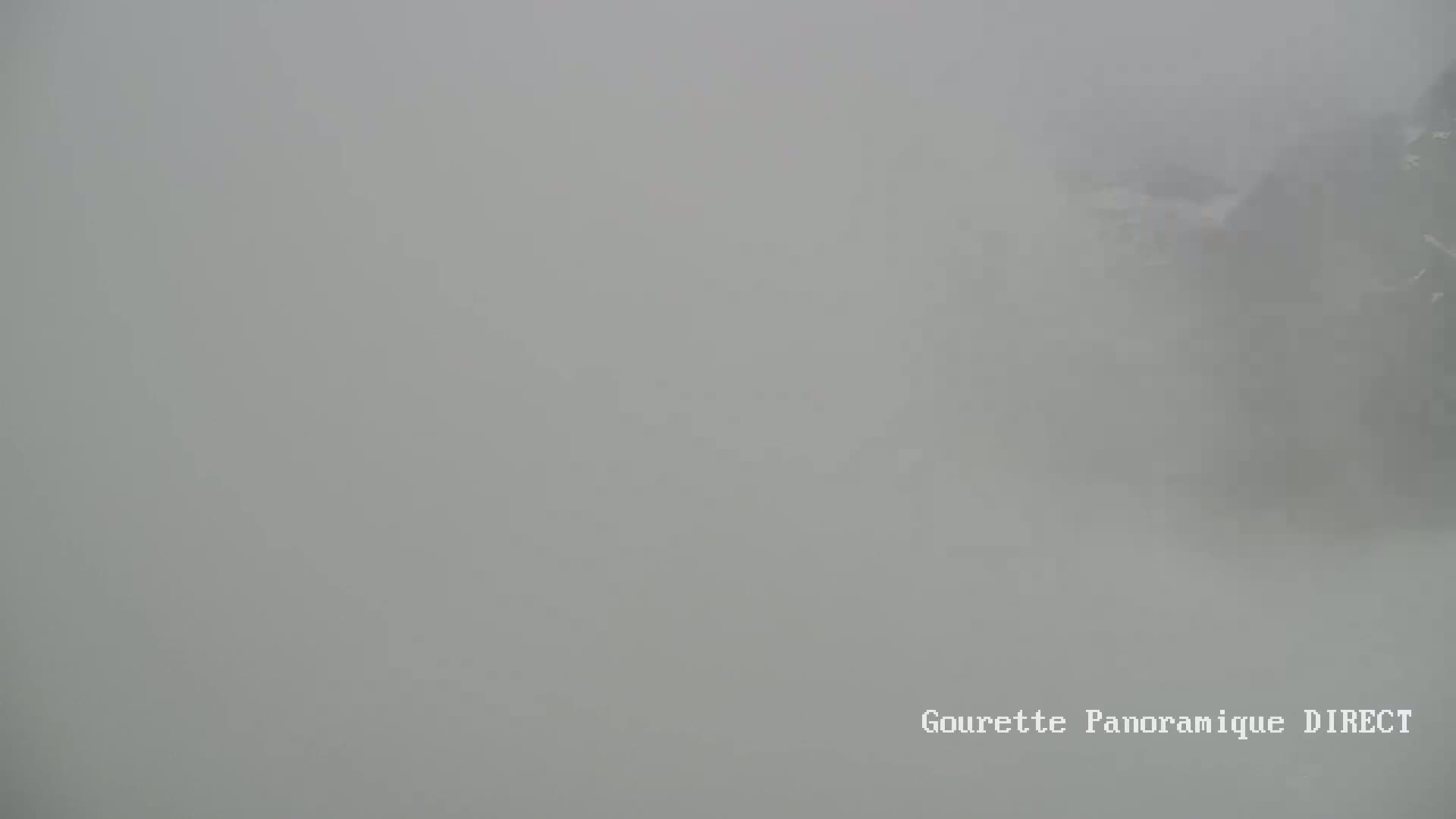 A very foggy or hazy outdoor scene shows indistinct shapes of what might be buildings or trees in the distance.