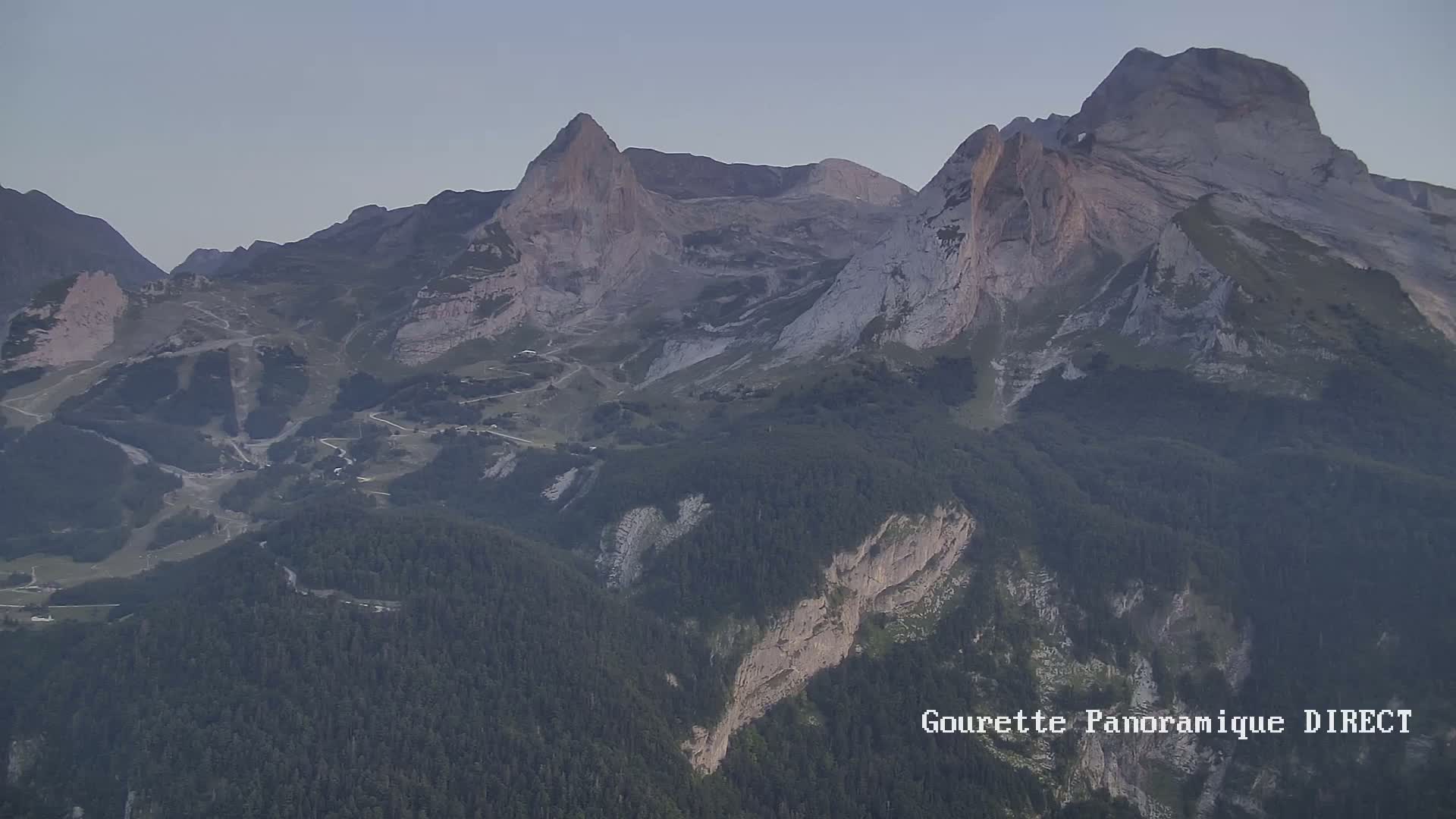 A long-range view shows a mountain range under a clear, light-blue sky.
