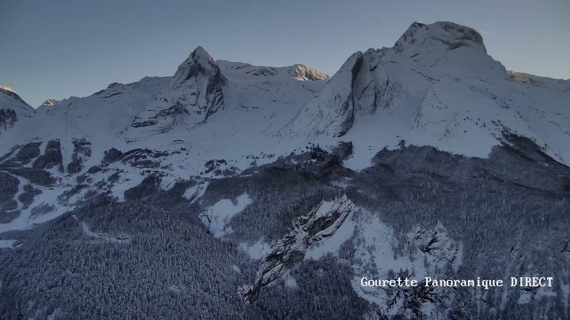 A long-range view shows a mountain range under a clear, light-blue sky.