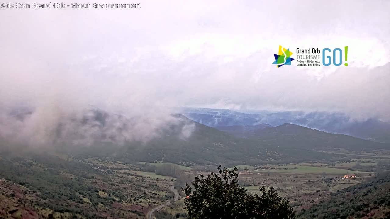 A misty, overcast day reveals a valley and distant mountains.