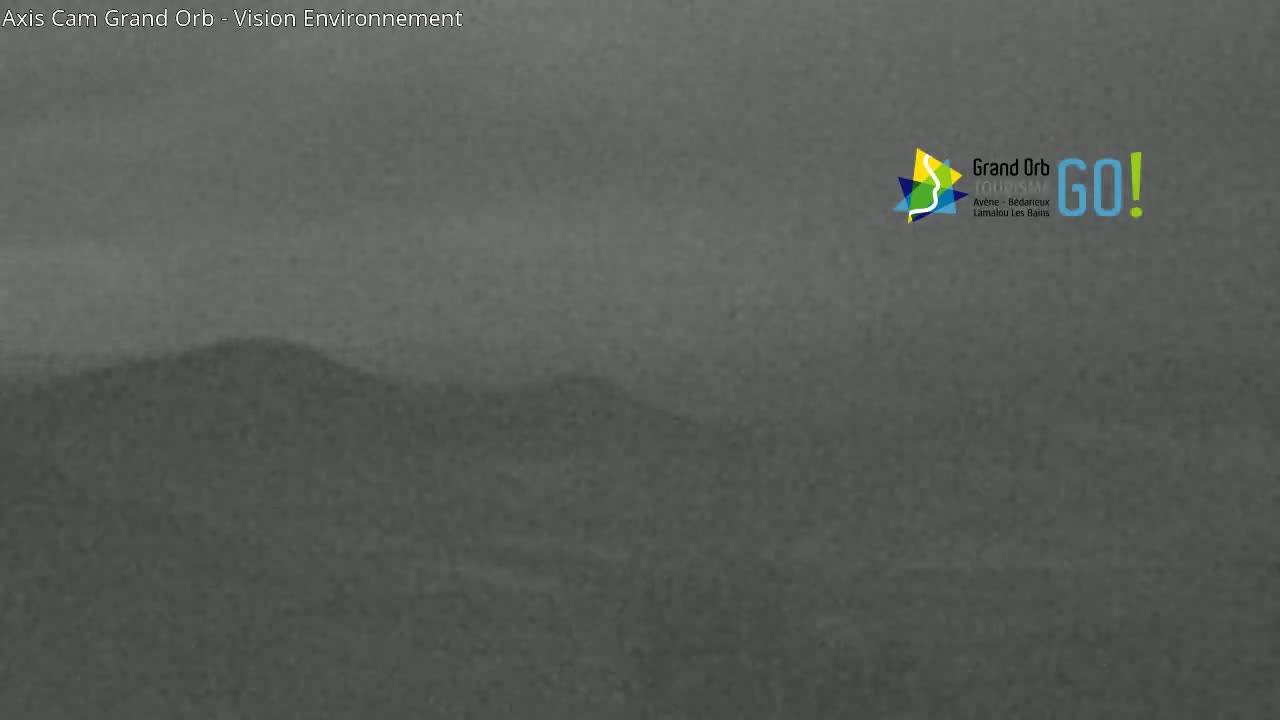 A hazy, overcast view shows a distant, low-lying hill.