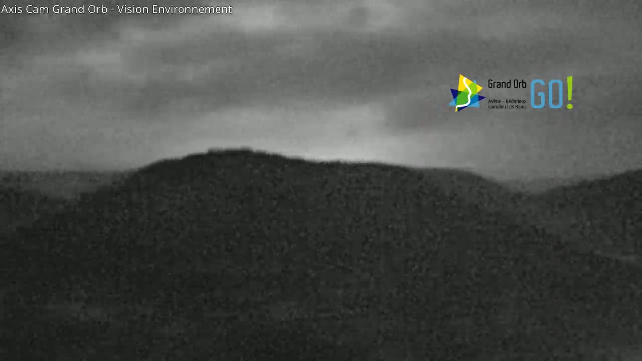 A dark, overcast sky hangs over a low, dark-colored hill.