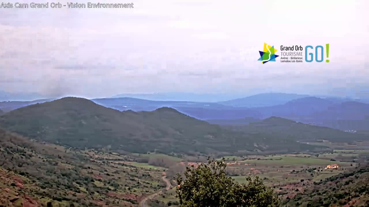 A panoramic view of rolling hills and valleys under a cloudy sky.