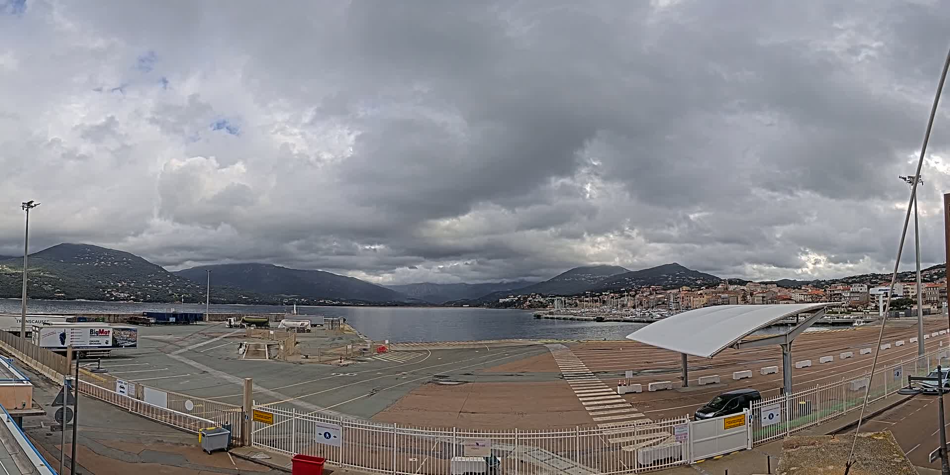 An empty port area with overcast skies and mountains in the distance.