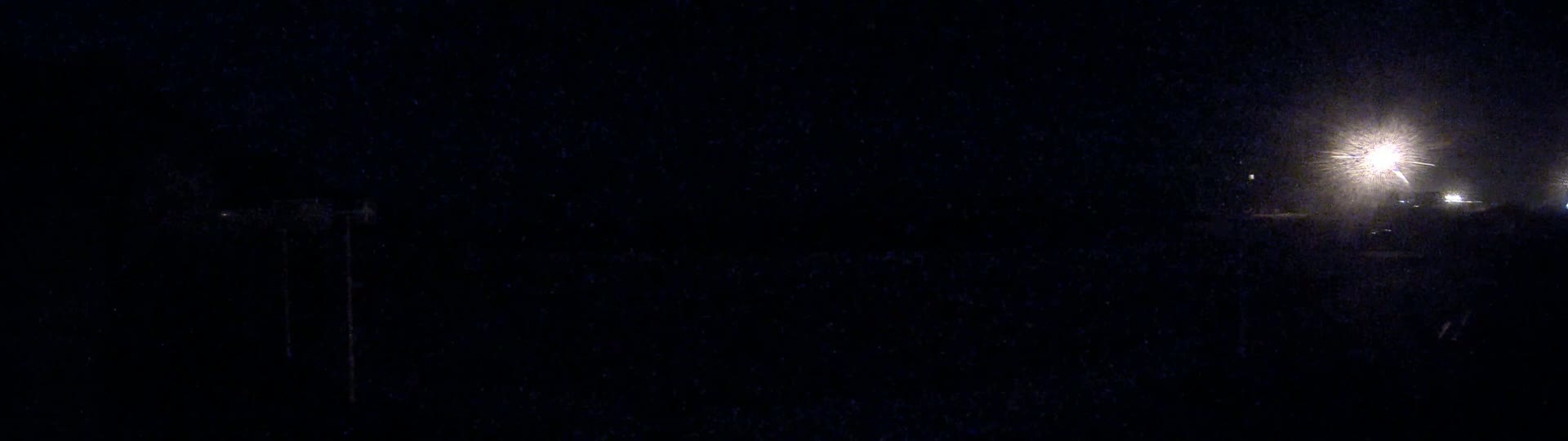 A dark, nighttime scene shows distant lights glowing brightly in the distance.