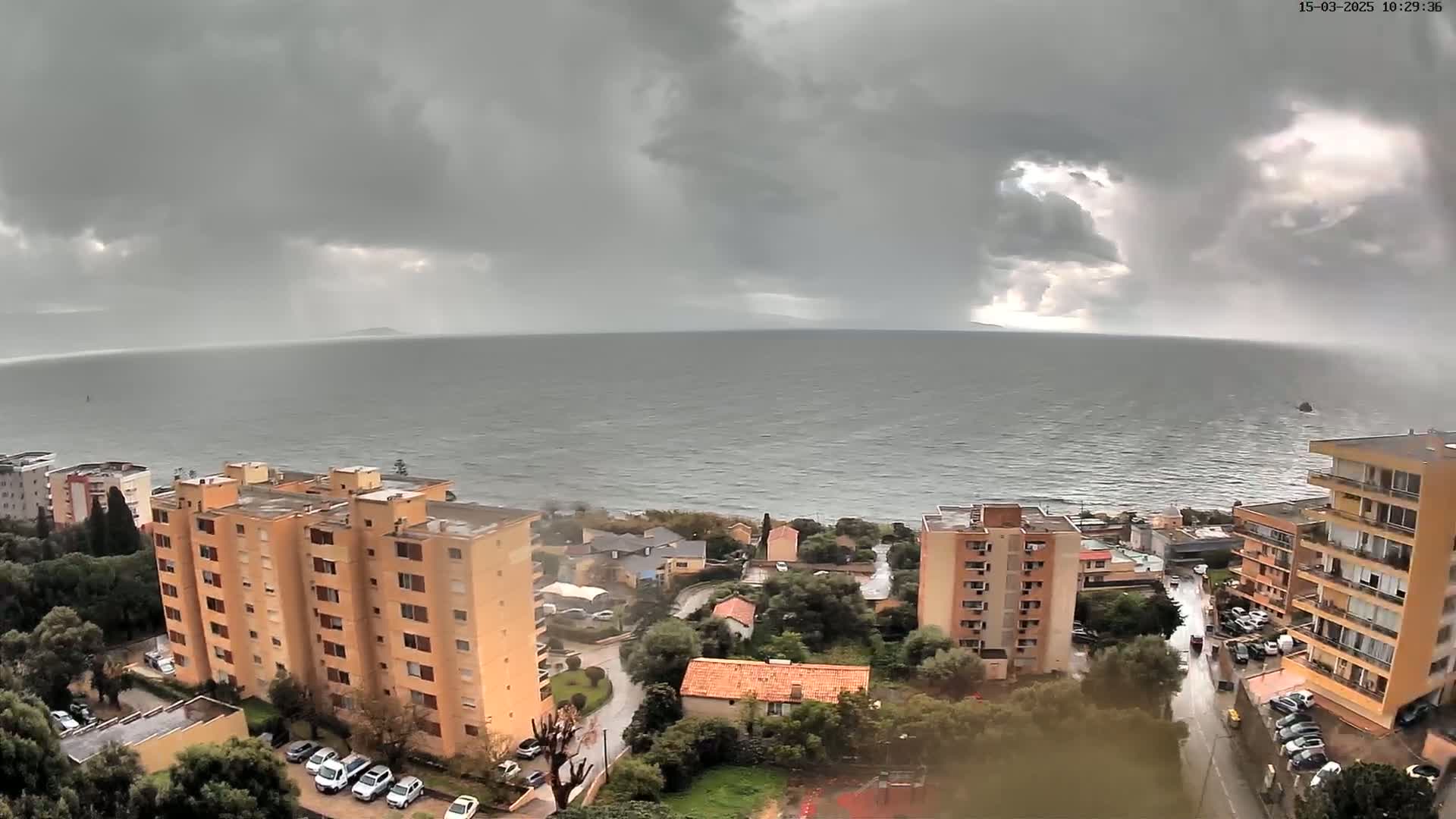 A coastal town under a stormy gray sky overlooks a choppy sea.