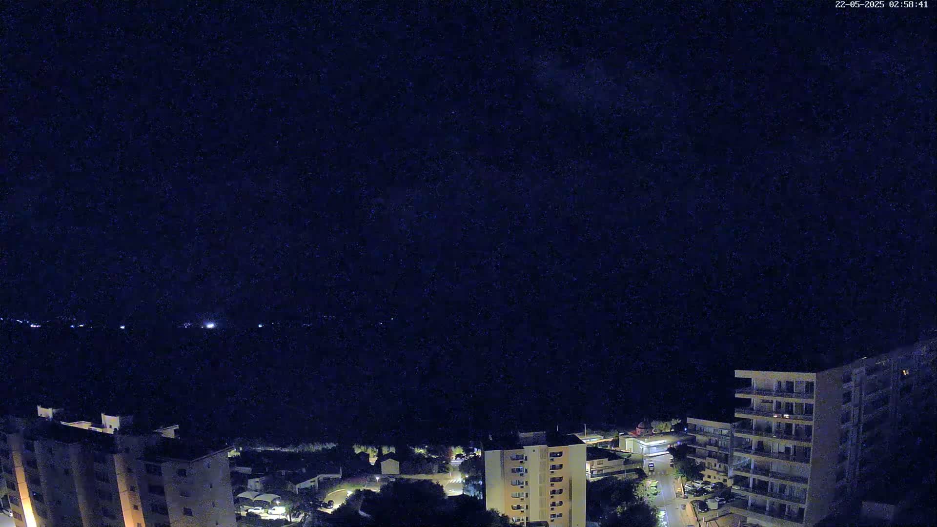 A nighttime aerial view of several apartment buildings illuminated against a dark, clear sky.