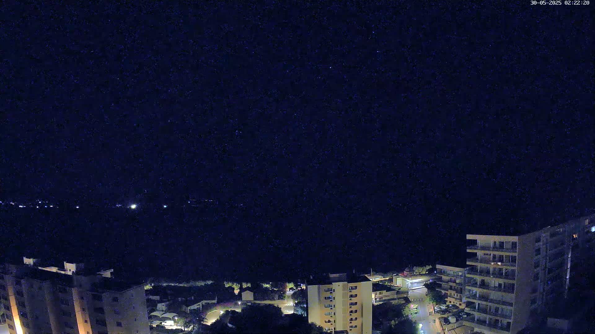 A nighttime view of a city with apartment buildings under a clear, starlit sky.